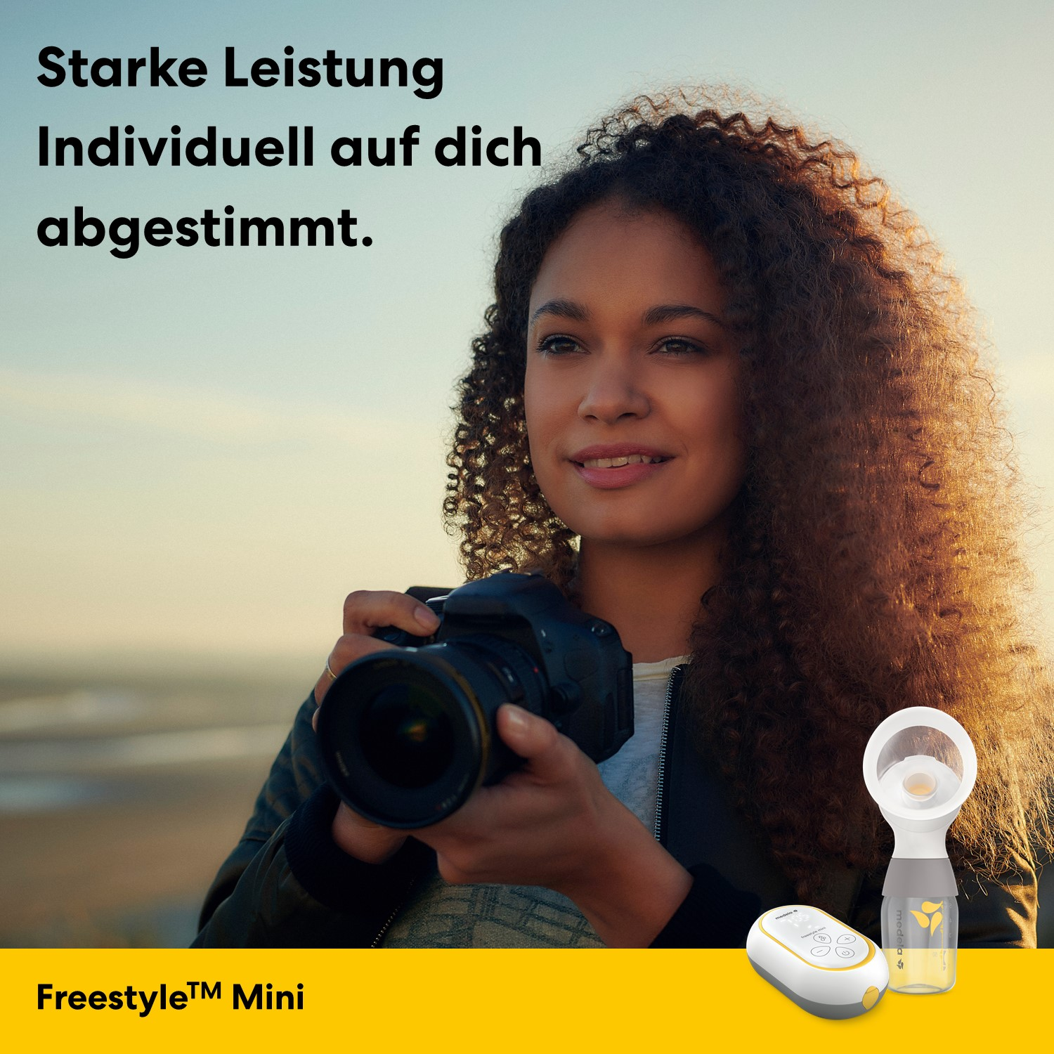 Frau mit Locken hält Kamera, daneben Milchpumpe und Steuergerät.