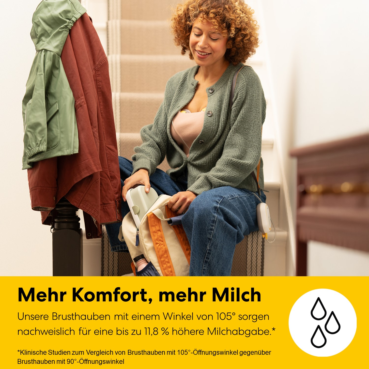 Eine Frau sitzt auf einer Treppe mit einem Rucksack und Kleidung auf einem Kleiderständer.