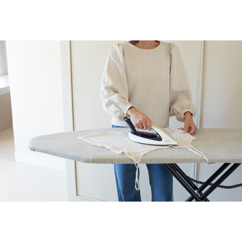 A person irons a polka dot garment on an ironing board.