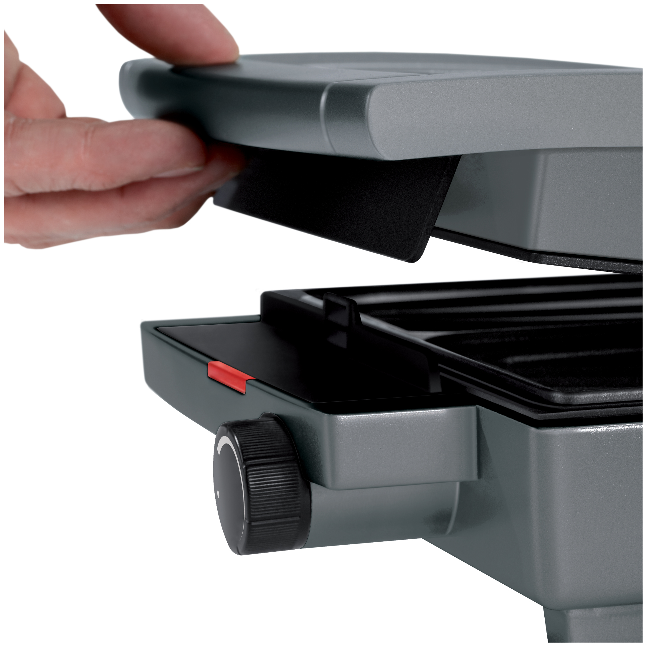 A hand closes a gray machine with a black dial and red lever.