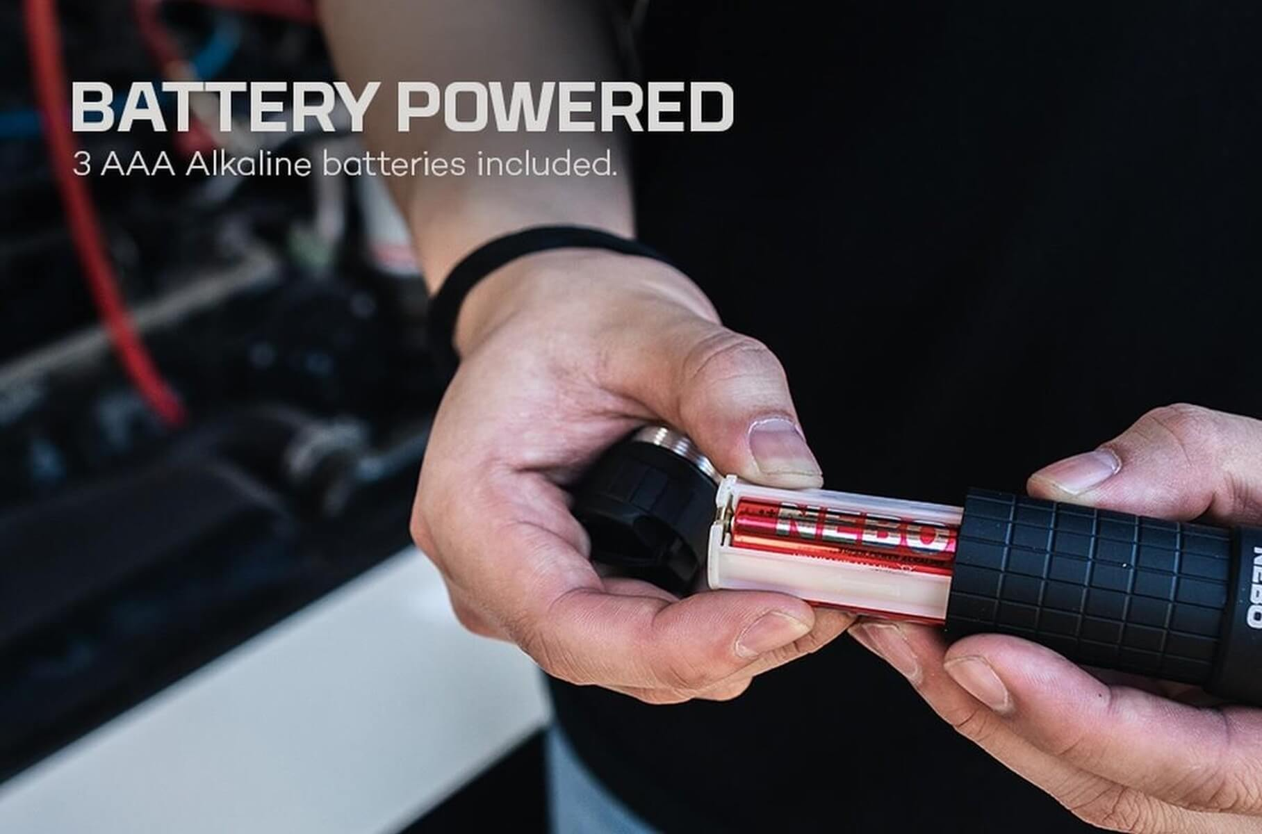 Persona inserisce 3 batterie AAA in una torcia nera.
