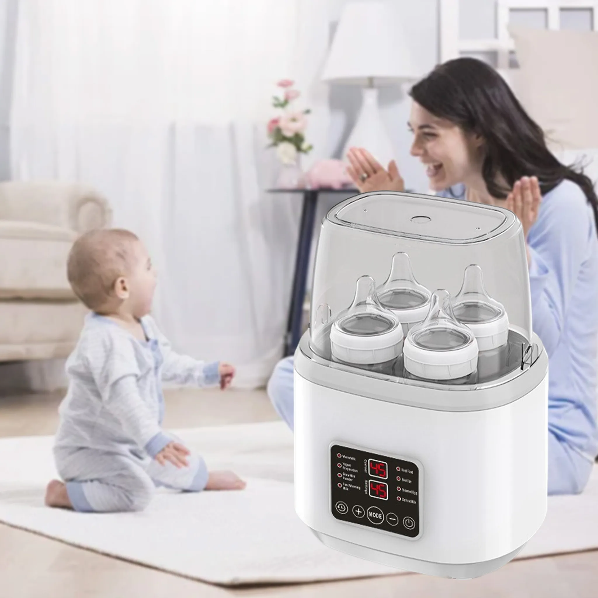 Ein Baby und eine Frau spielen neben einem Flaschensterilisator im Haus.
