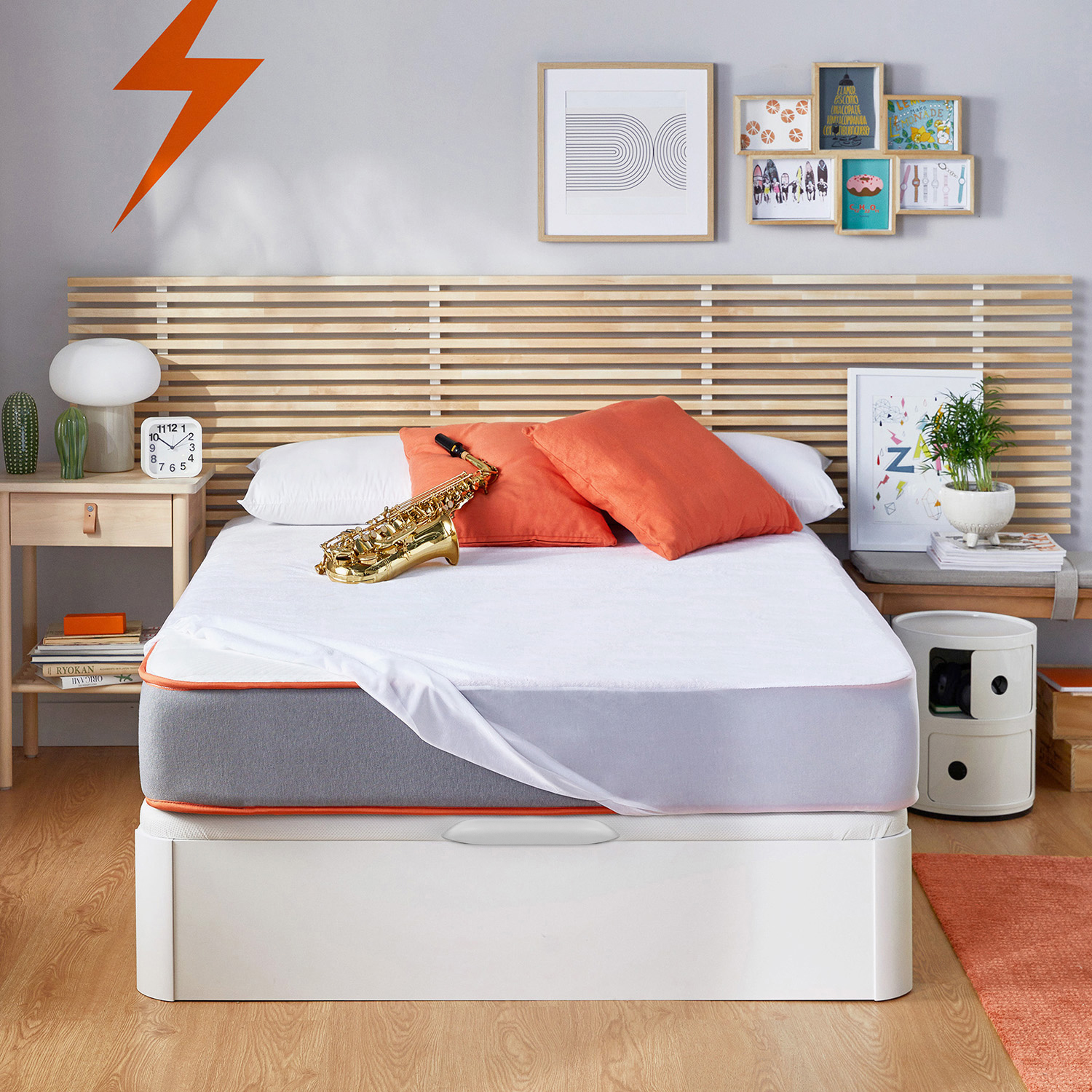 Una cama con cojines naranjas, un saxofón y arte en la pared.