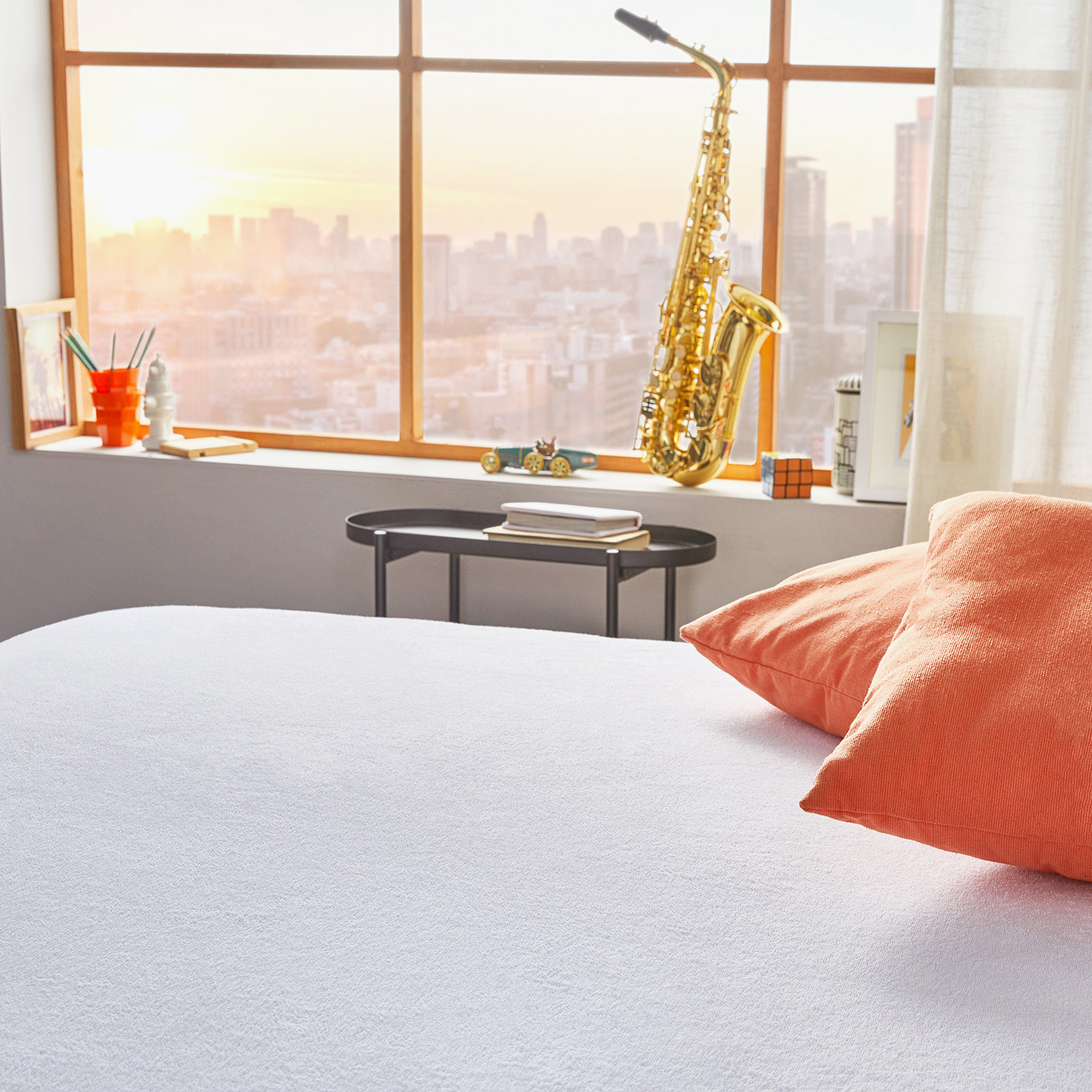 Saxofón en alféizar con vistas al horizonte urbano al atardecer, cama al frente.