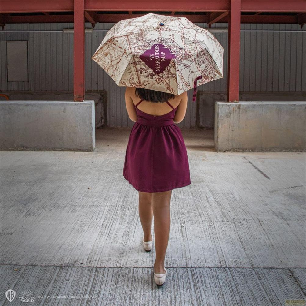 Eine Frau mit einem Regenschirm, der die Karte der
Umtreiber zeigt, geht auf einem Betonweg.
