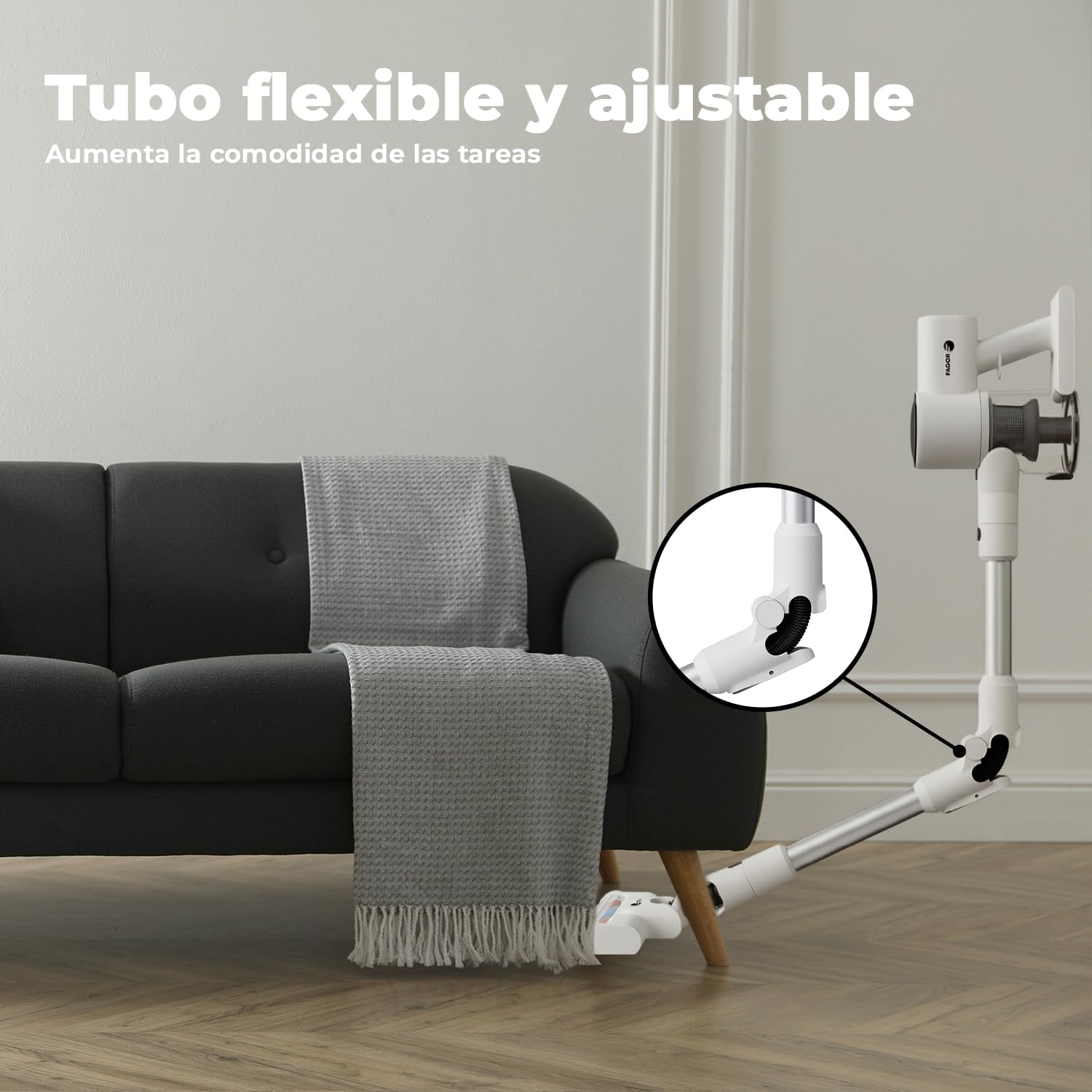 Una aspiradora blanca con tubo flexible debajo de un sofá con mantas grises.
