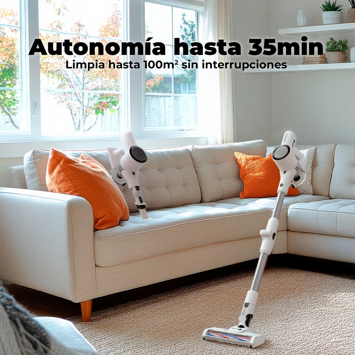 Un aspirador inalámbrico blanco está sobre una alfombra frente a un sofá.