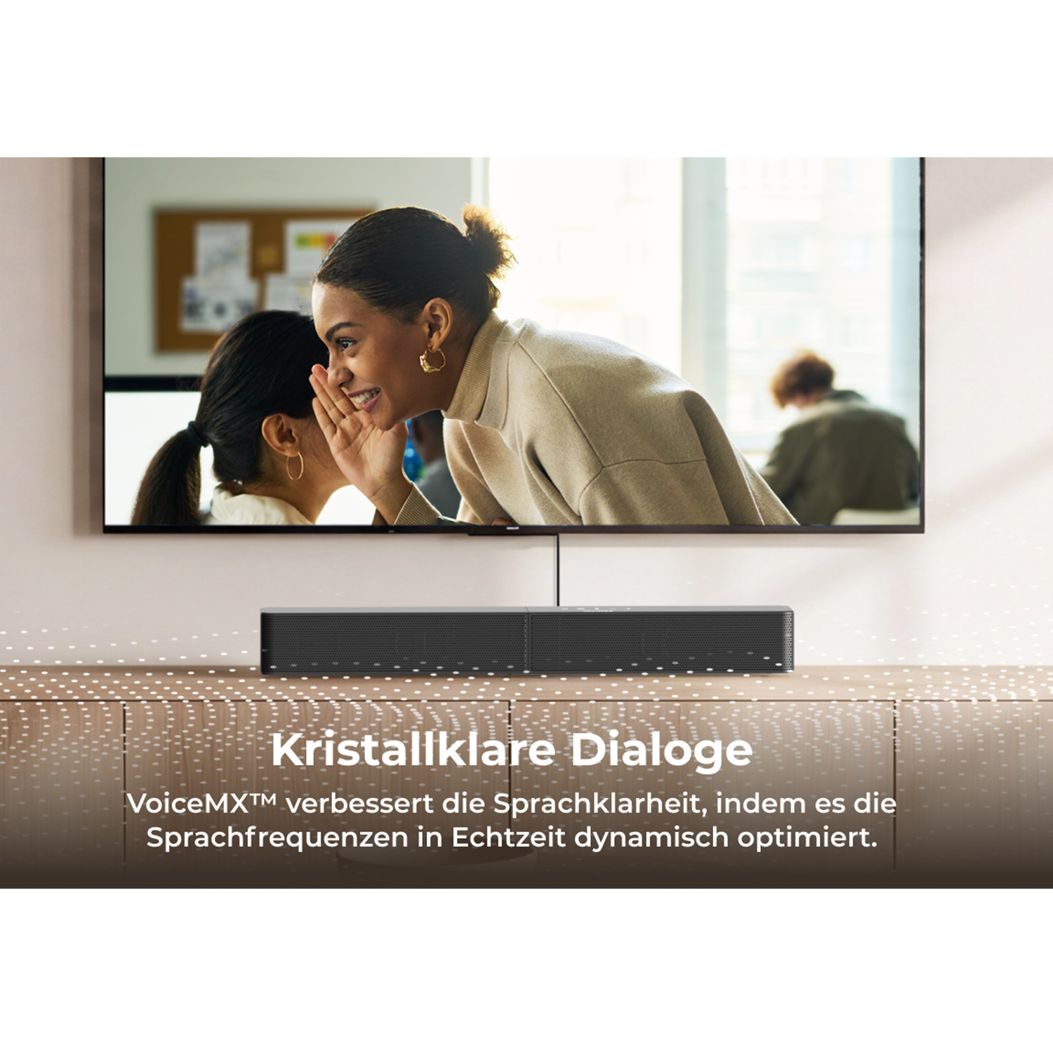 Zwei Frauen flüstern, eine Soundbar steht vor einem TV mit Büroszene.