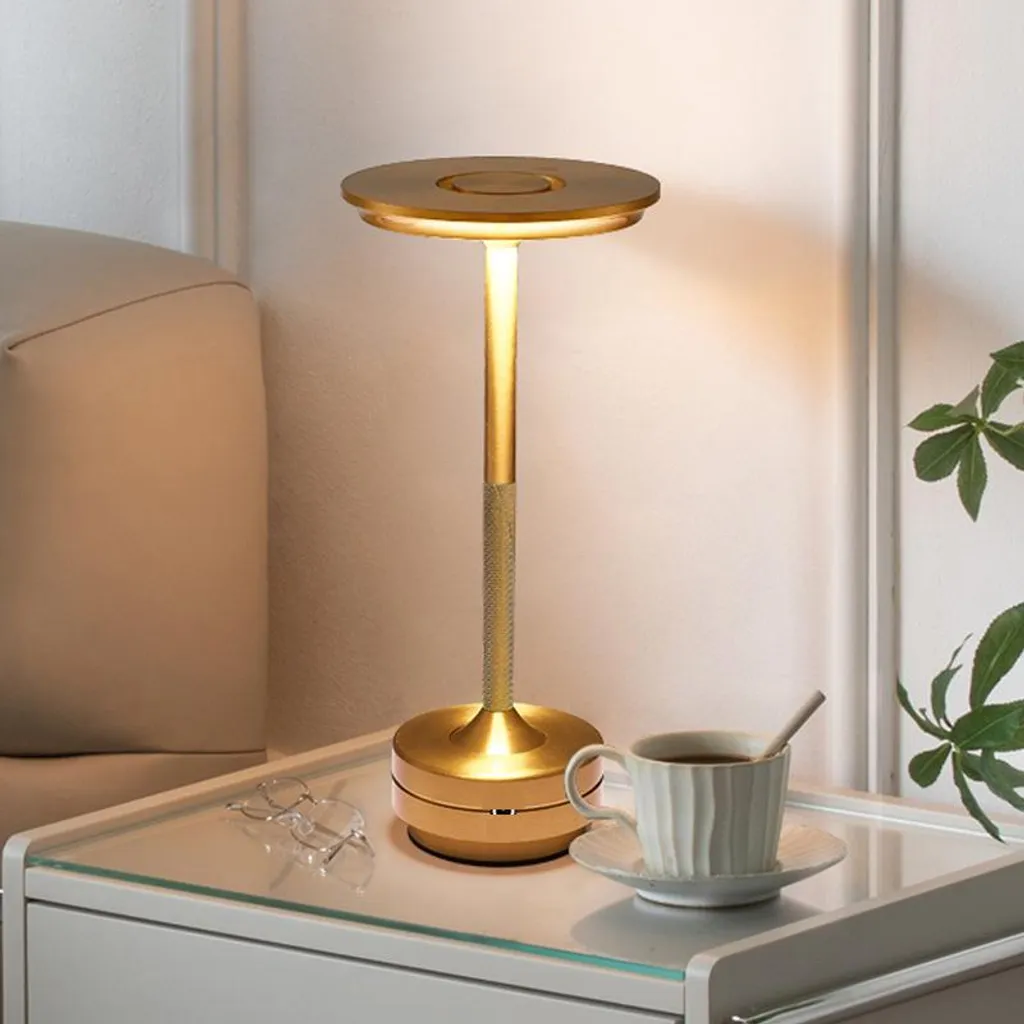 Goldene Lampe auf Nachttisch mit Tasse Kaffee und Brille.