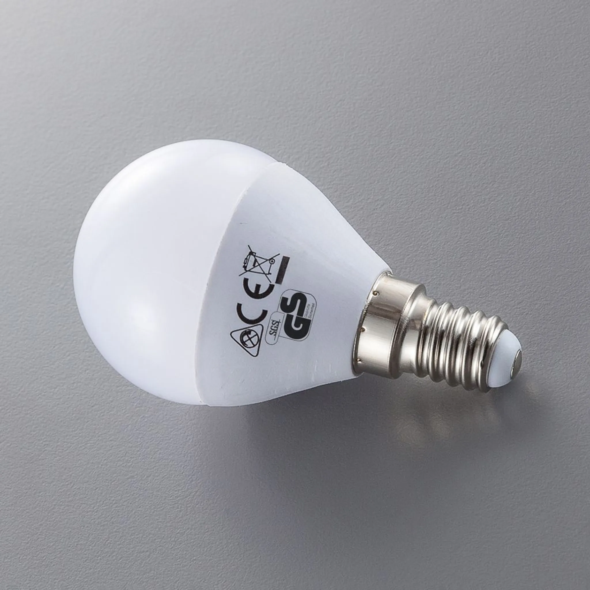 Eine weiße LED-Glühbirne mit E14-Schraubfassung liegt auf grauem Grund.