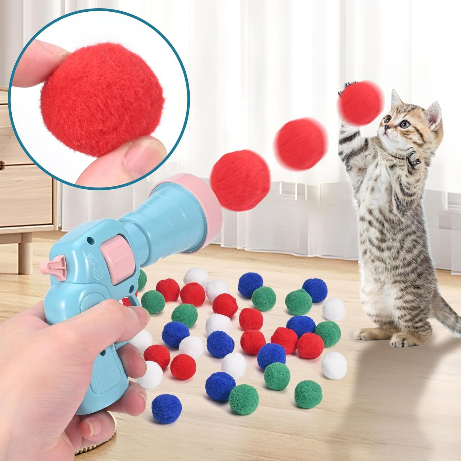 Katze spielt mit Ballwerfer und bunten Pompons auf dem Boden.
