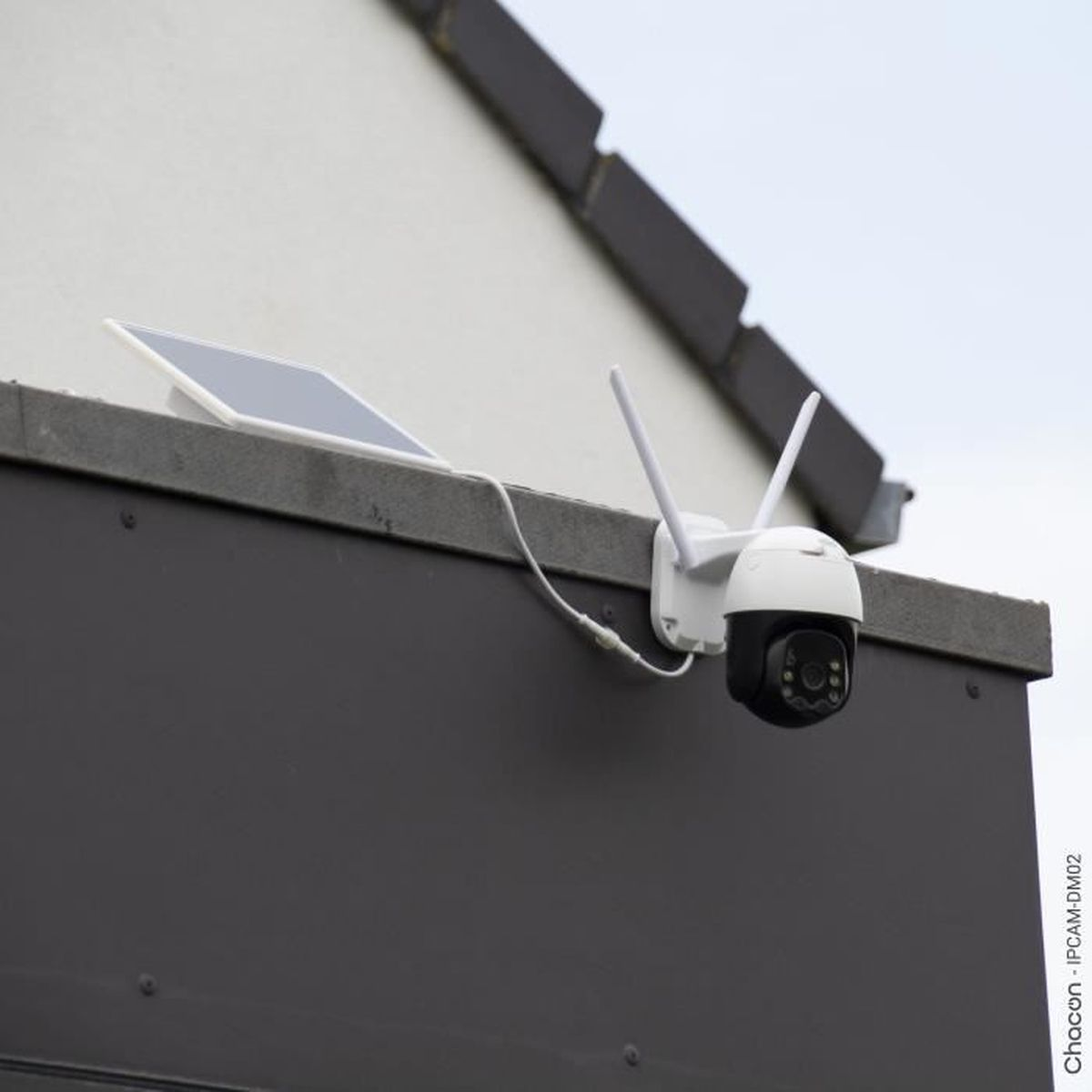 Een witte beveiligingscamera met zonnepaneel is op een donkere muur gemonteerd.