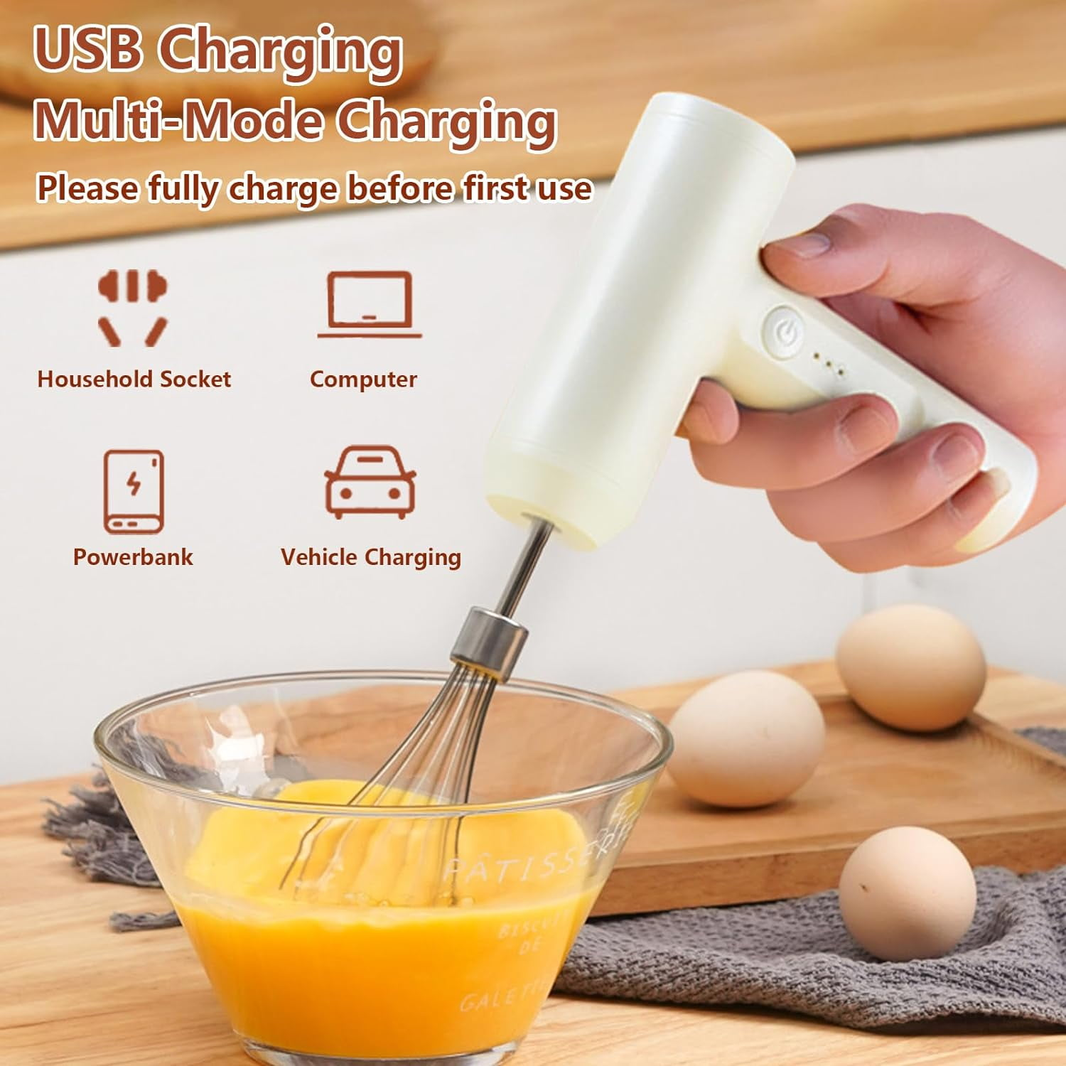 Ein weißer Handmixer mit Quirl über einer Schüssel mit Eigelb, Eier daneben.