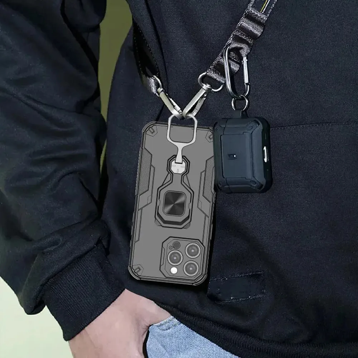 Une personne porte un sweat à capuche noir avec un téléphone et des écouteurs suspendus à un cordon.