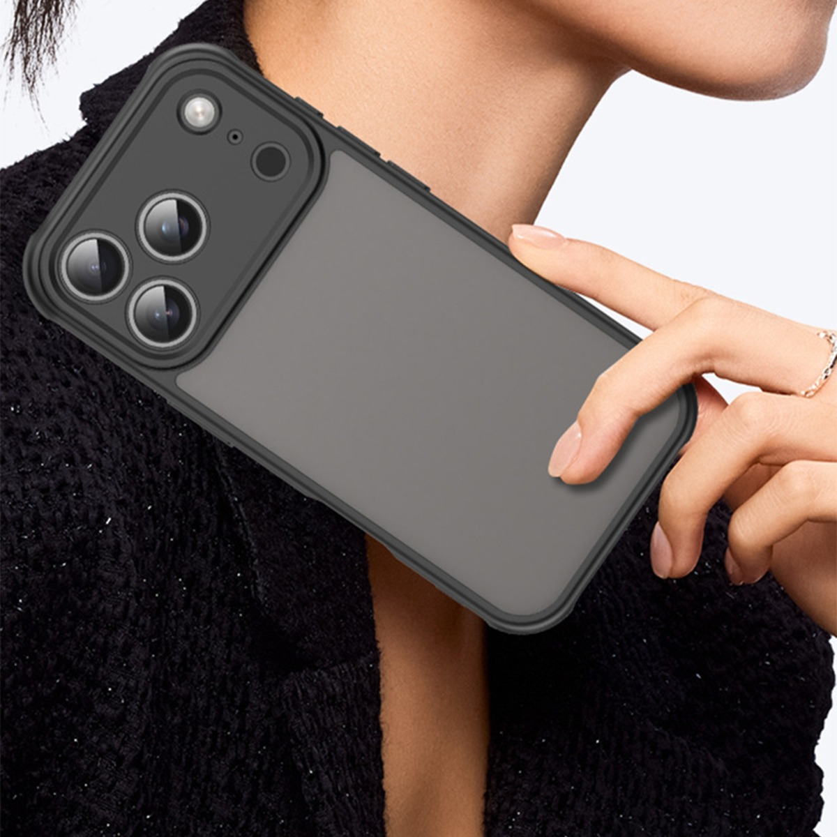Una persona tiene una custodia grigia per iPhone con copriobiettivo. Un anello adorna il dito.