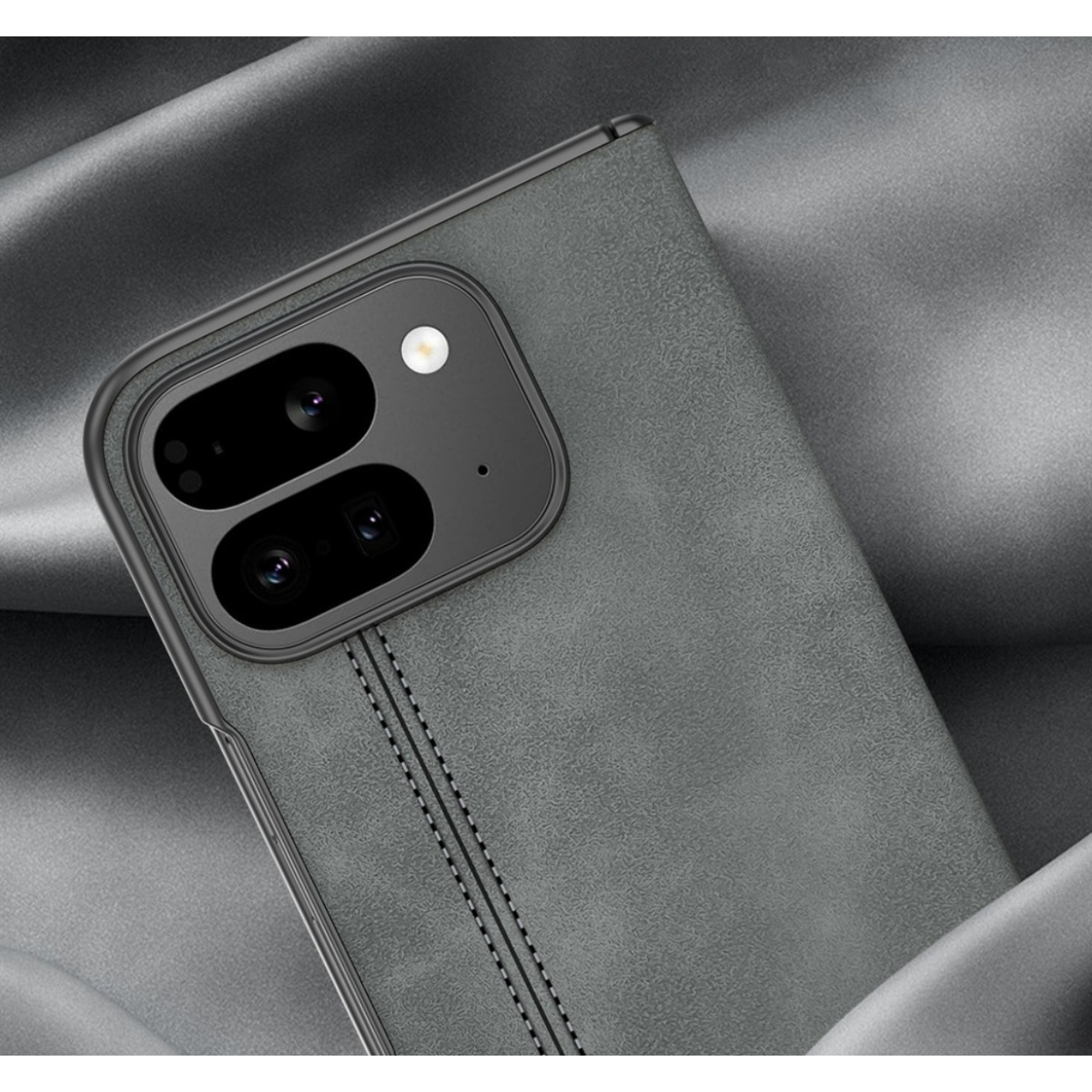 Primo piano di una custodia grigia per telefono con doppia fotocamera e flash, su sfondo di seta grigia.