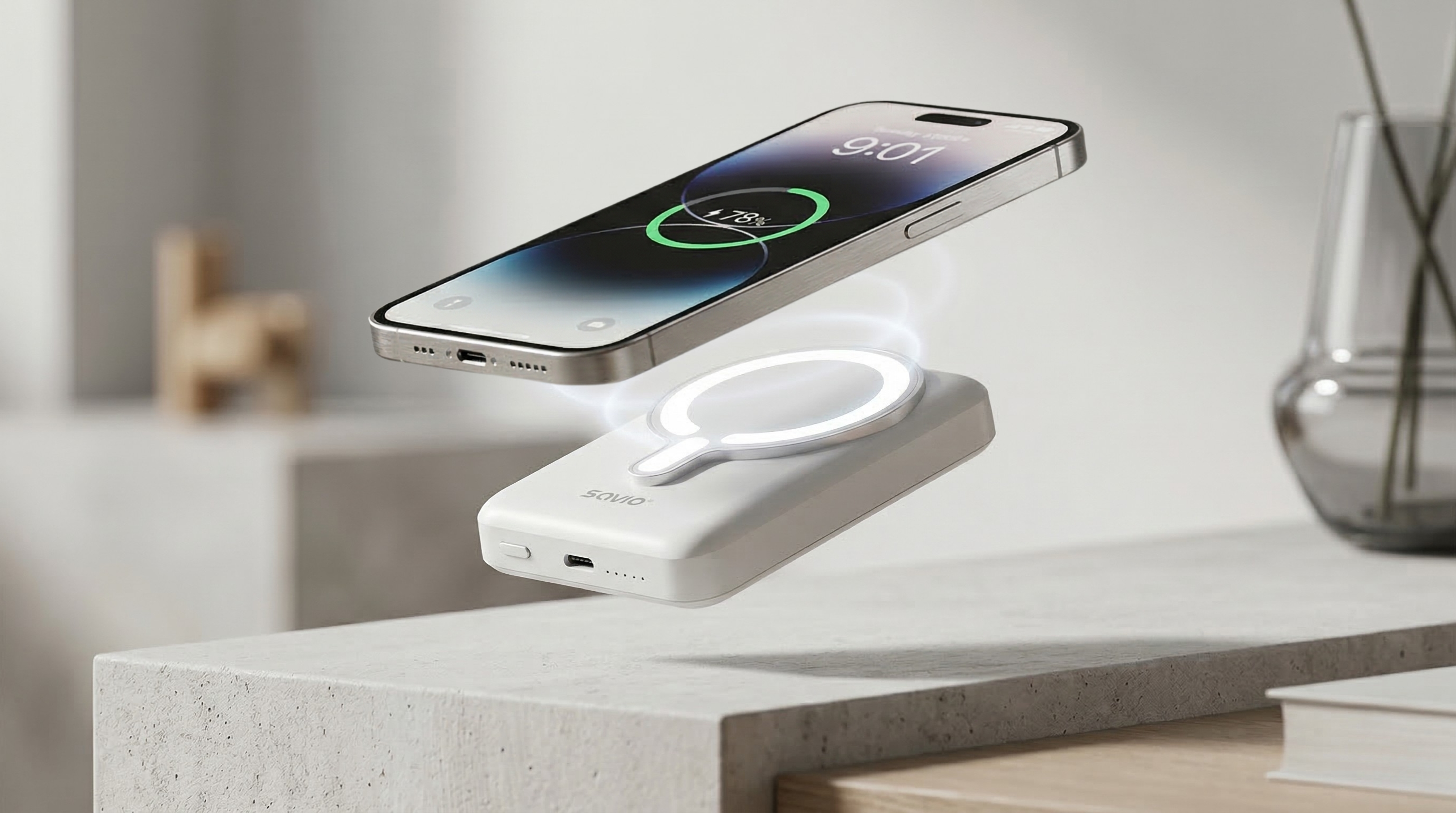 Biała ładowarka i srebrny iPhone unoszą się nad betonowym stojakiem.