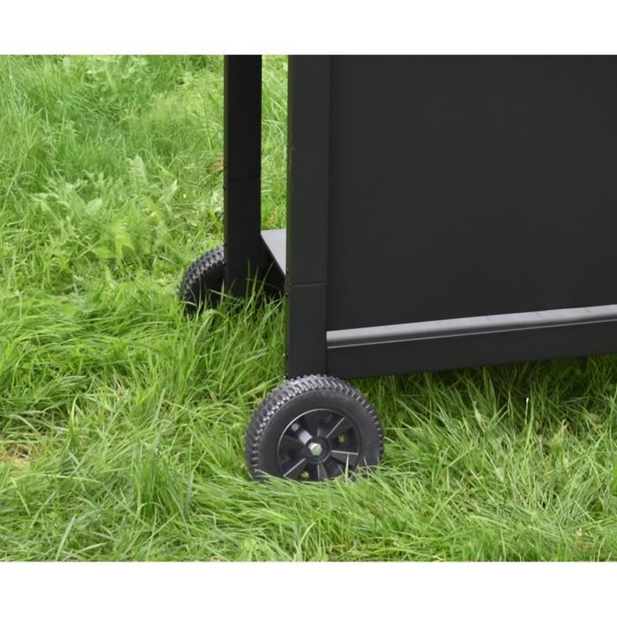Ein schwarzer Grill mit Rädern steht auf grünem Gras.