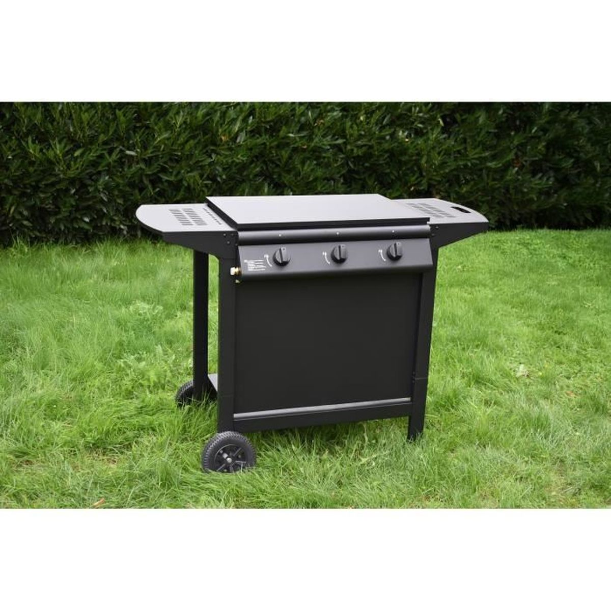 Ein schwarzer Gasgrill mit drei Knöpfen steht auf einem grünen Rasen.