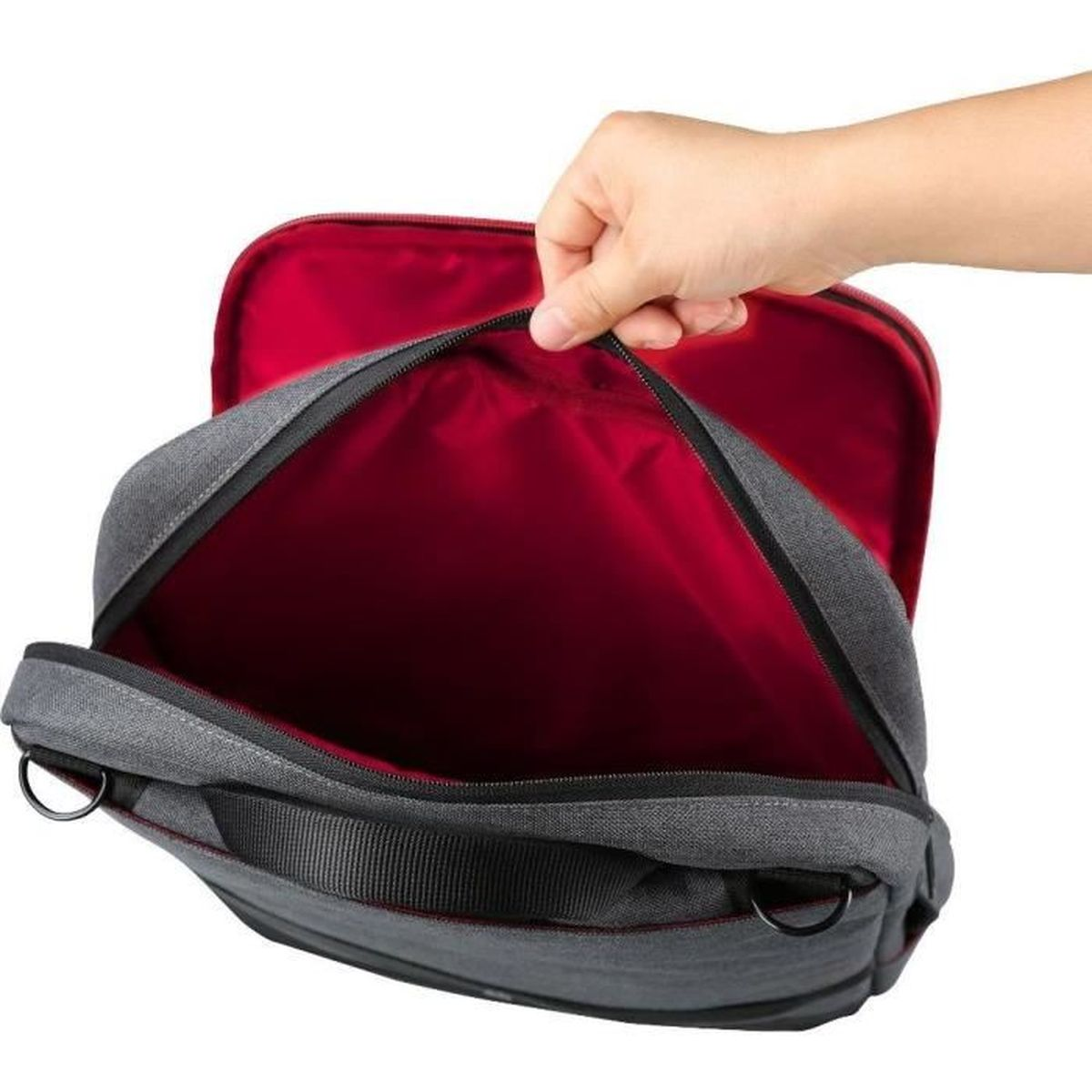 Una mano chiude una borsa grigia con fodera interna rossa.