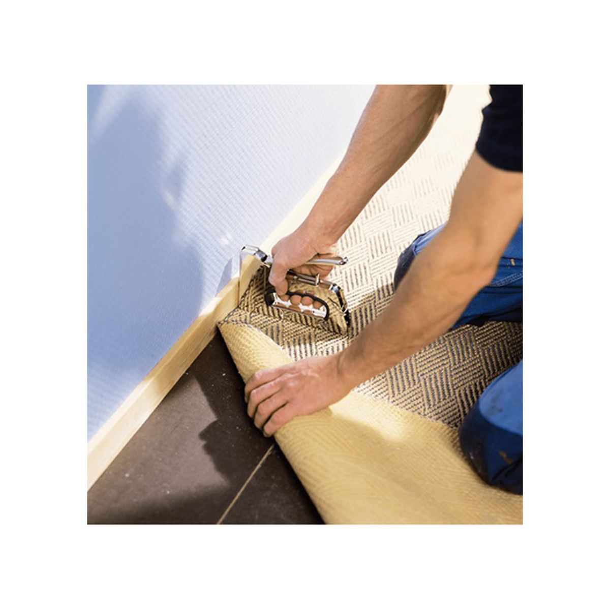 Hände heften Teppichkante an Wandleiste. Beige gemusterter Teppich gerollt.