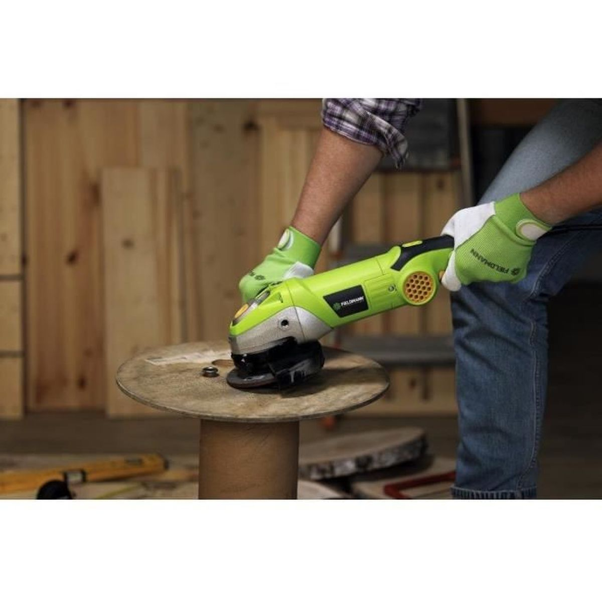 Zielona szlifierka kątowa w ręku, pracująca na drewnianej tarczy.
