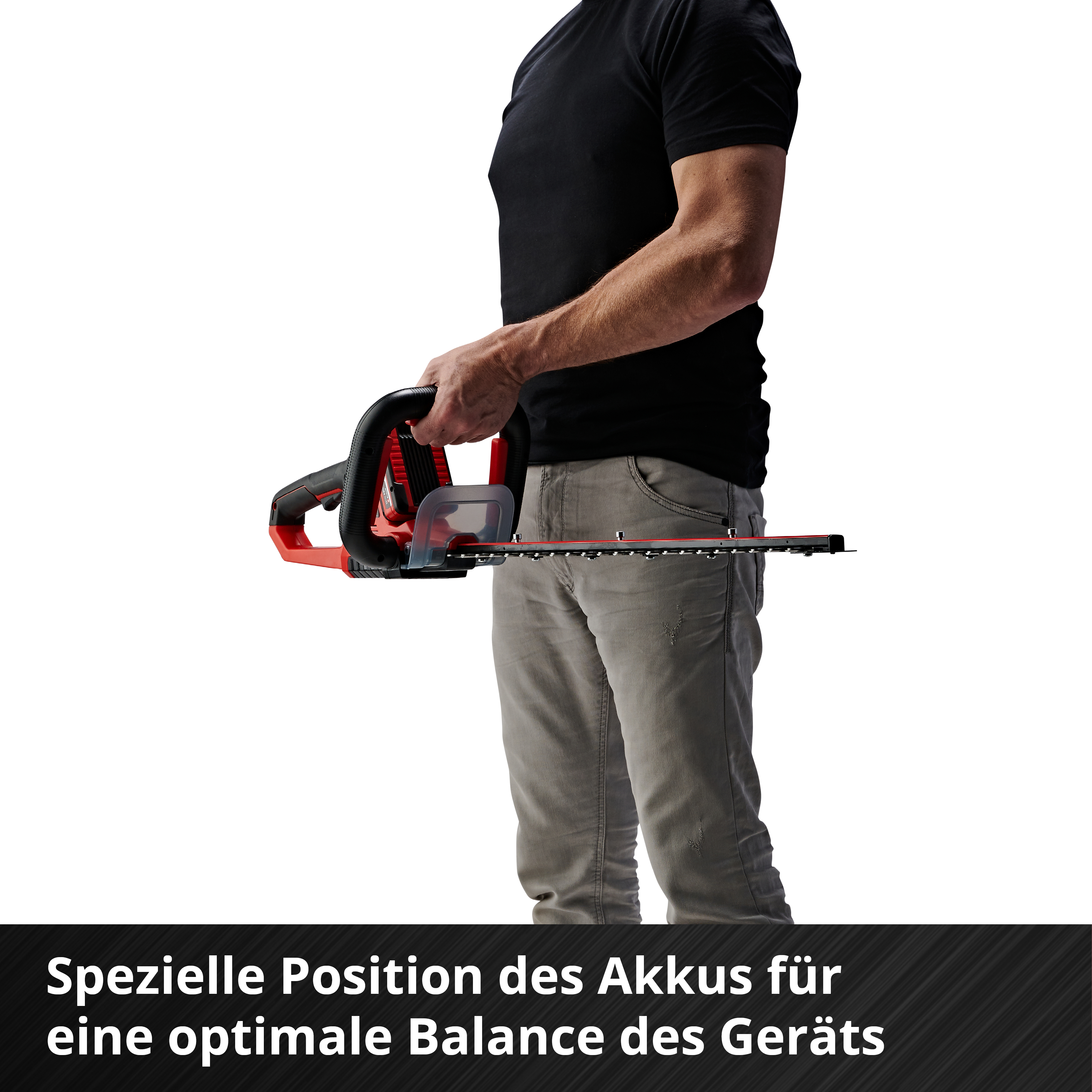Homme tenant un taille-haie, haut noir, pantalon gris. Position spéciale batterie.