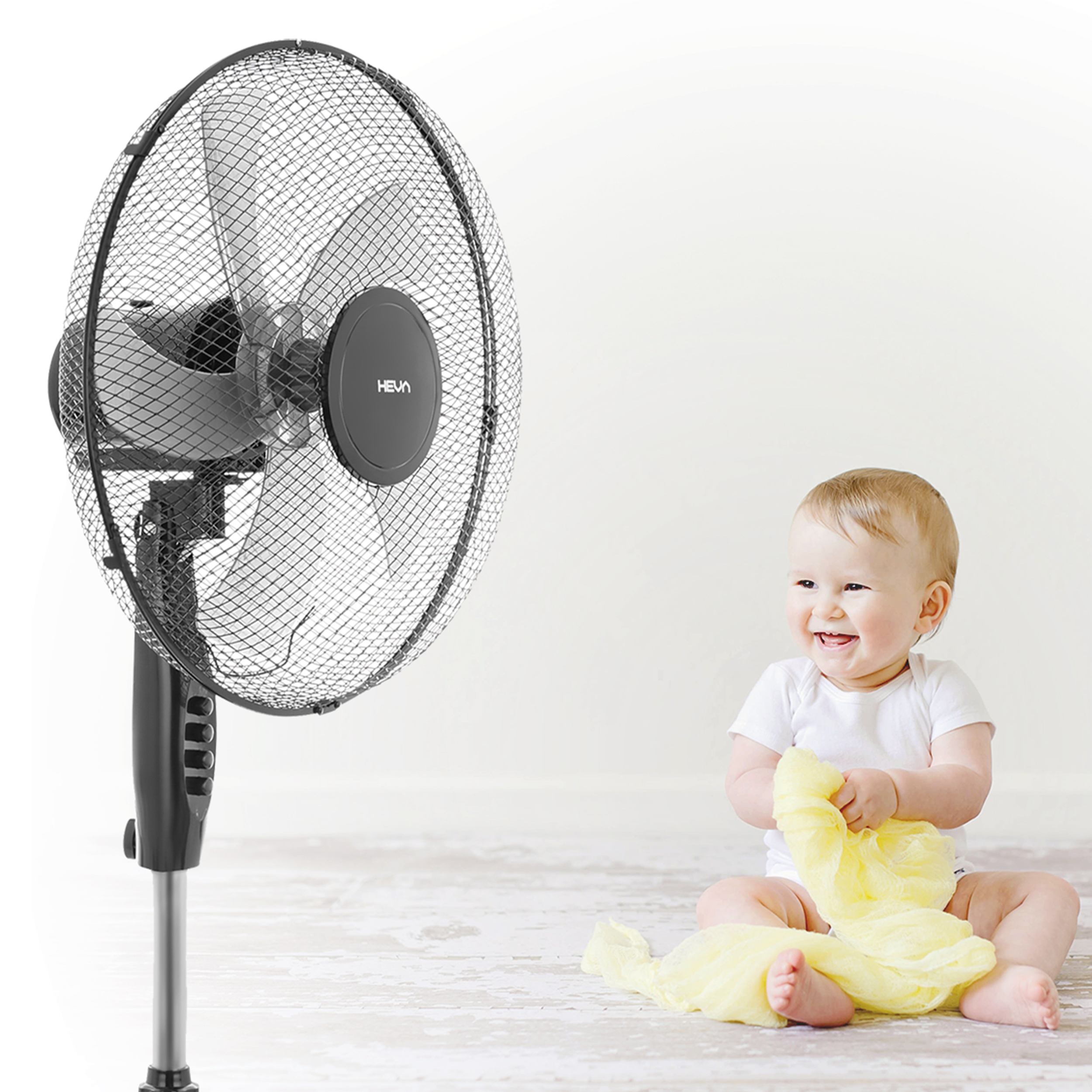 Niemowlę bawi się żółtą tkaniną obok wentylatora.