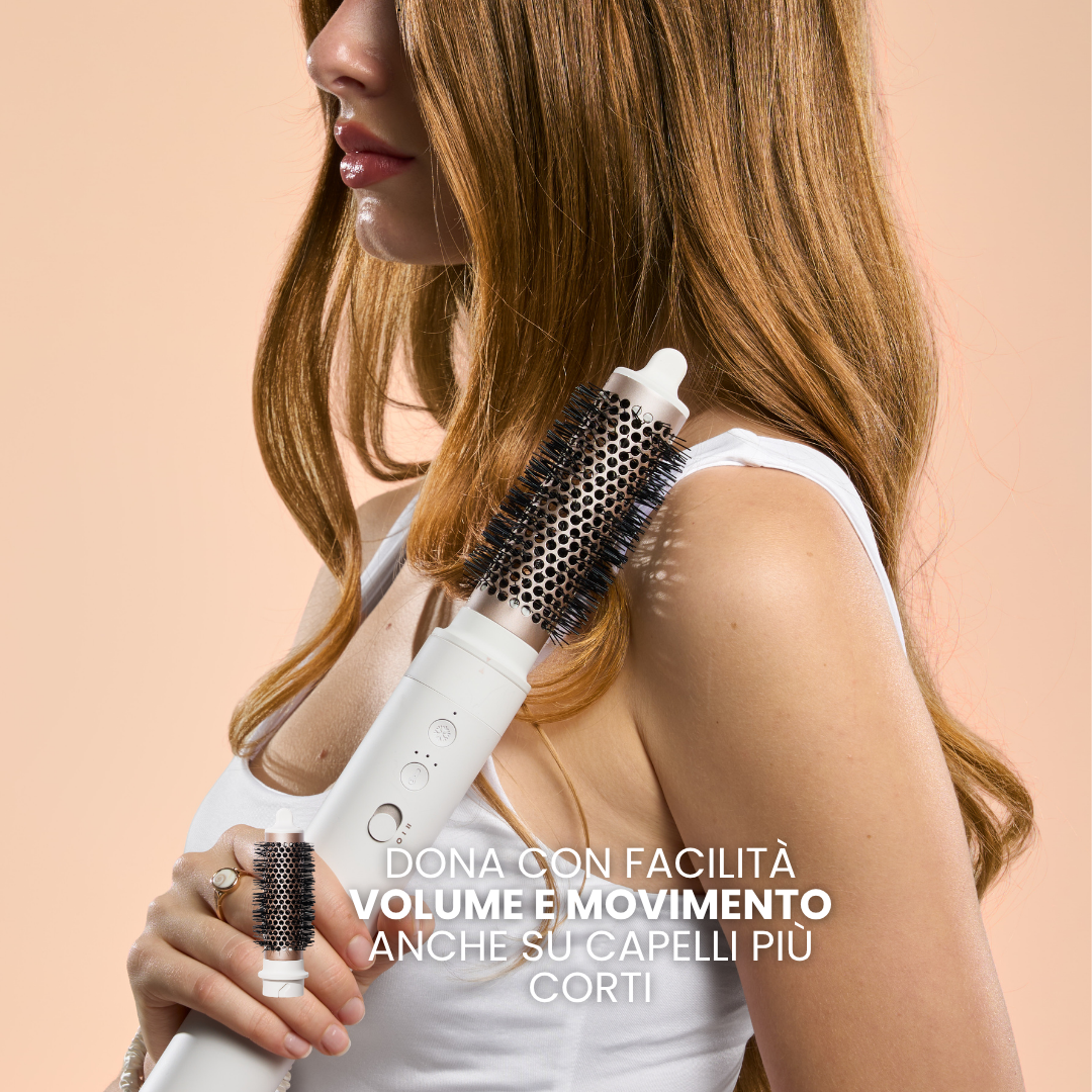 Donna con spazzola rotante bianca che pettina i suoi lunghi capelli ramati.