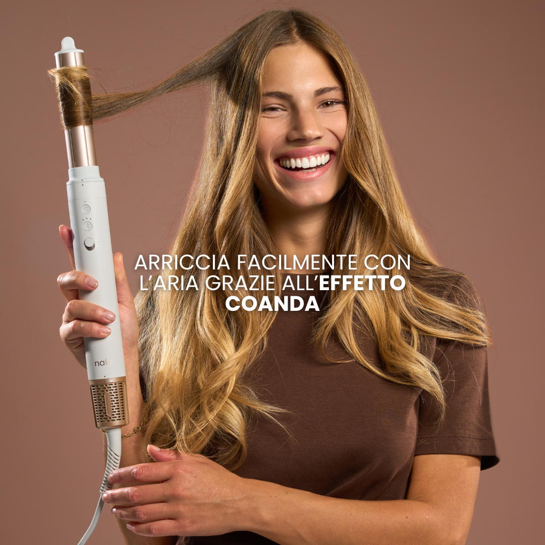 Donna con top marrone tiene un styler bianco e oro, arricciando i capelli.