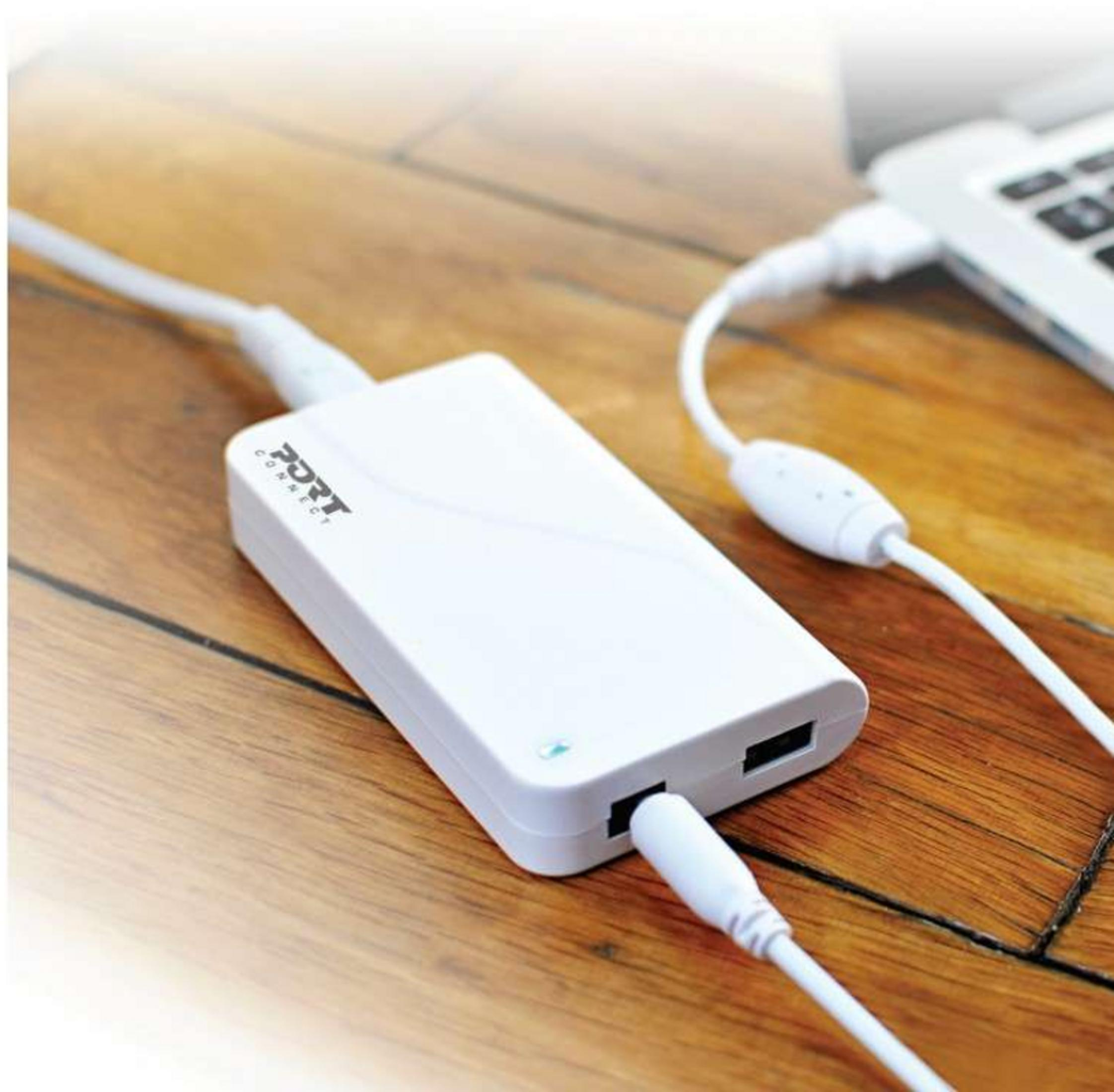 Un hub USB bianco carica un laptop su un tavolo di legno.