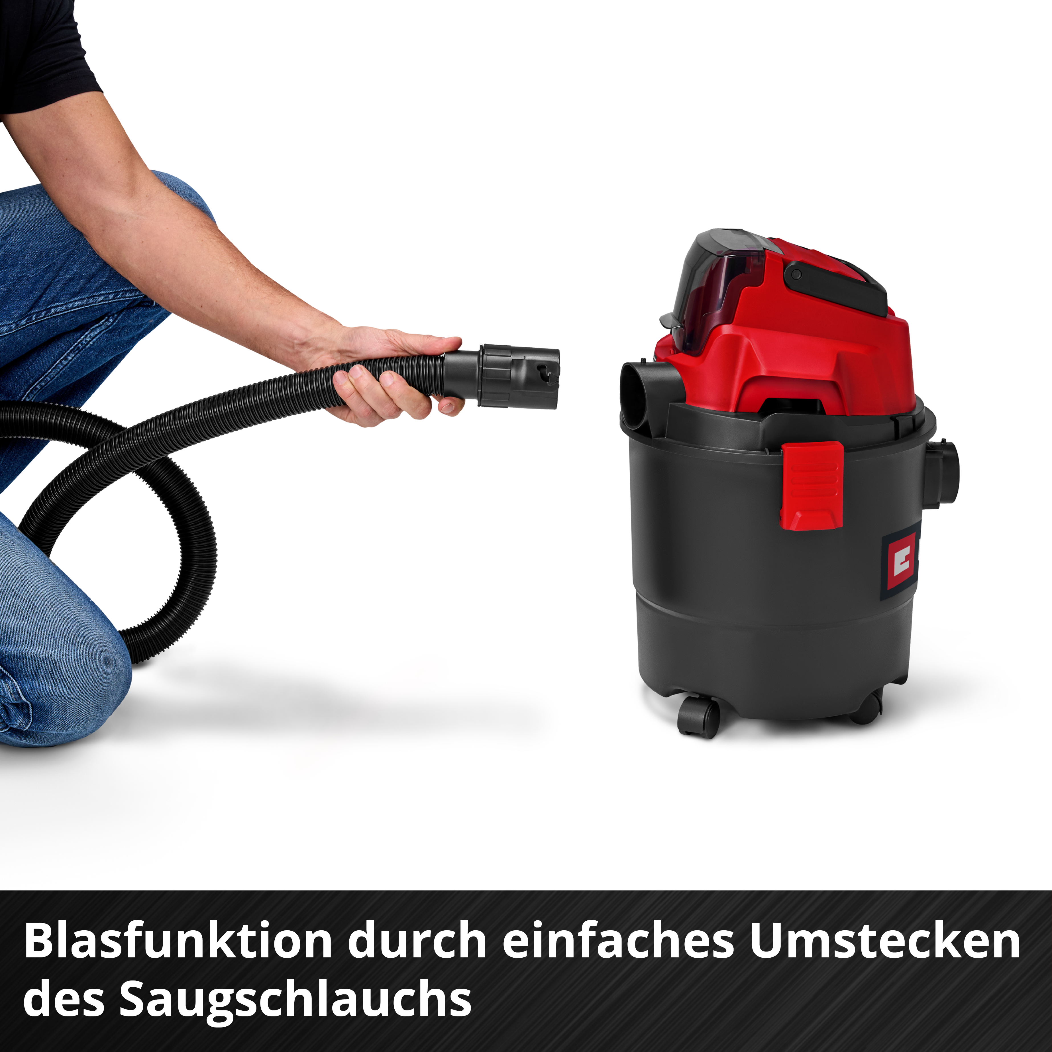 Un homme raccorde un tuyau à un aspirateur eau et poussière noir et rouge.