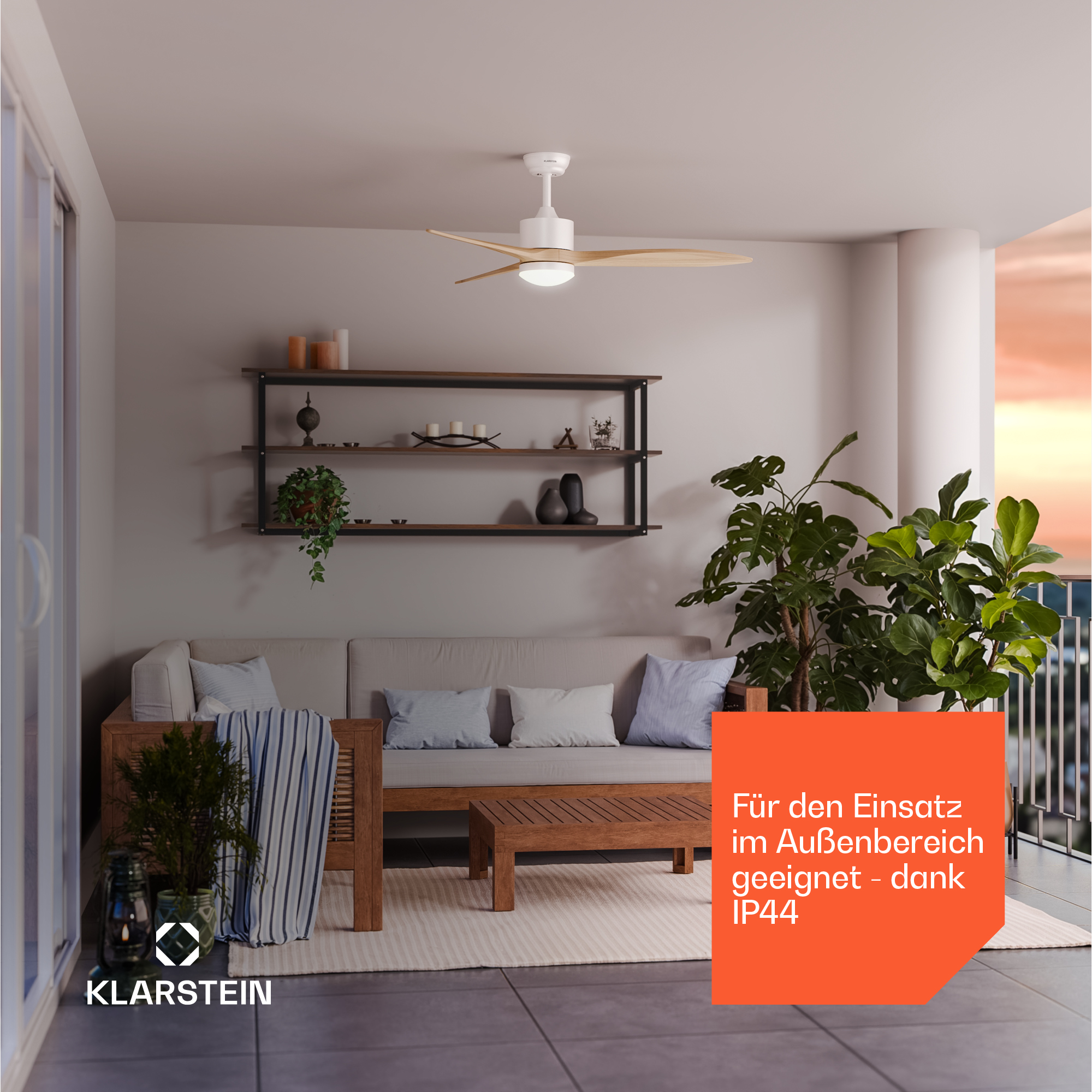 Ein Deckenventilator mit Holzflügeln über einem Sofa auf einem Balkon.