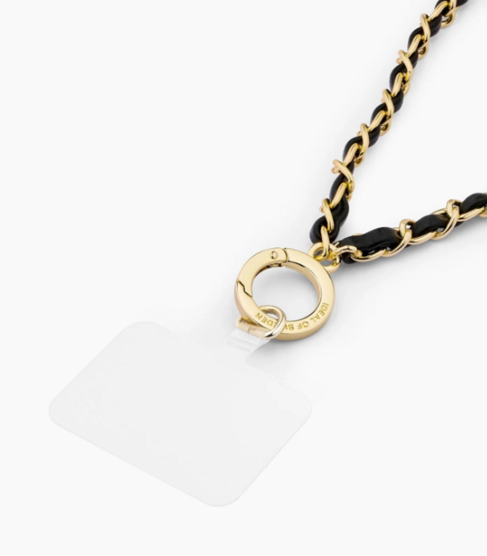 Schwarze und goldene Kette mit einem Ring und einem transparenten Anhänger.