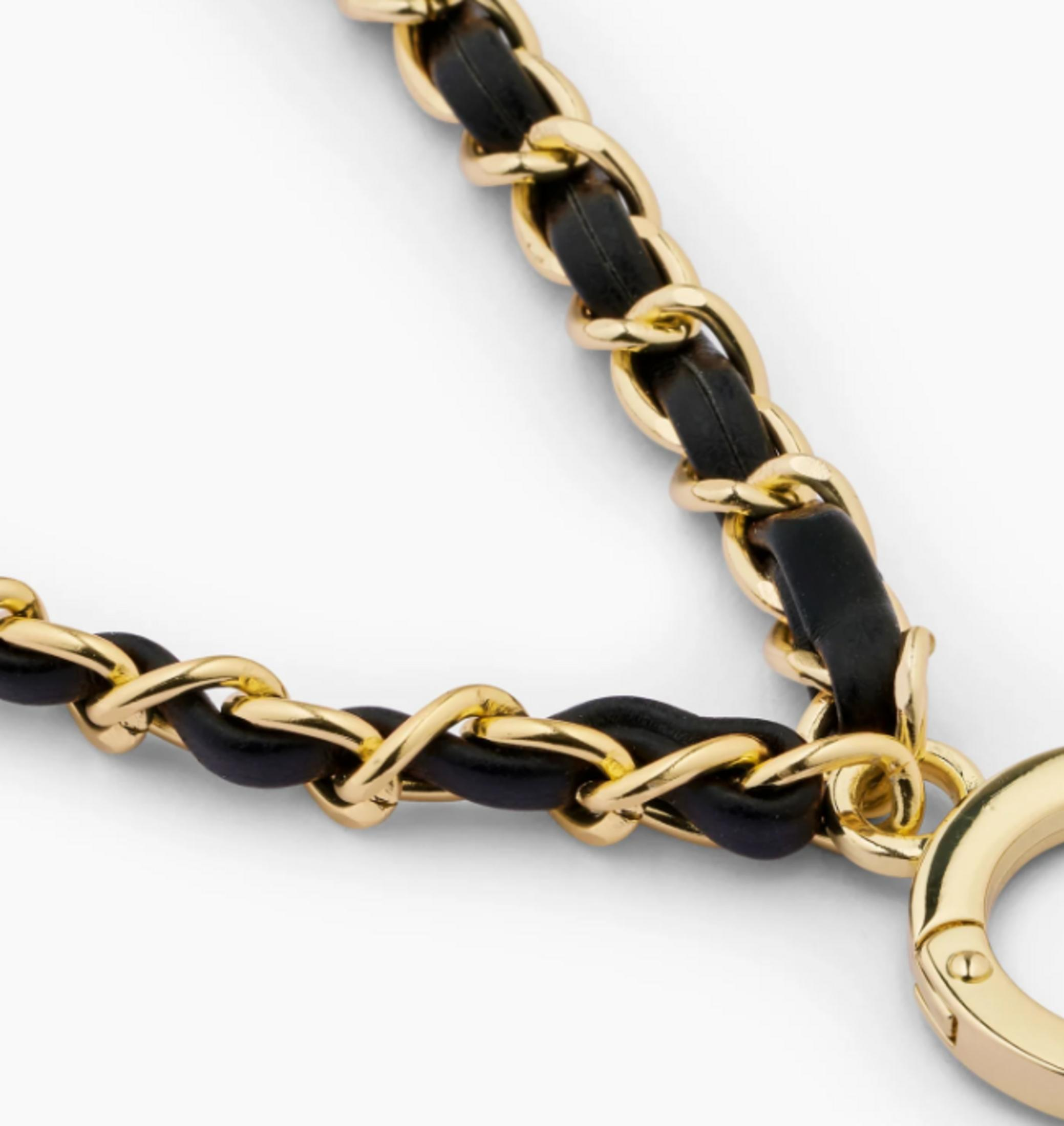 Goldene Kette mit schwarzen Lederdetails und einem runden Verschluss.