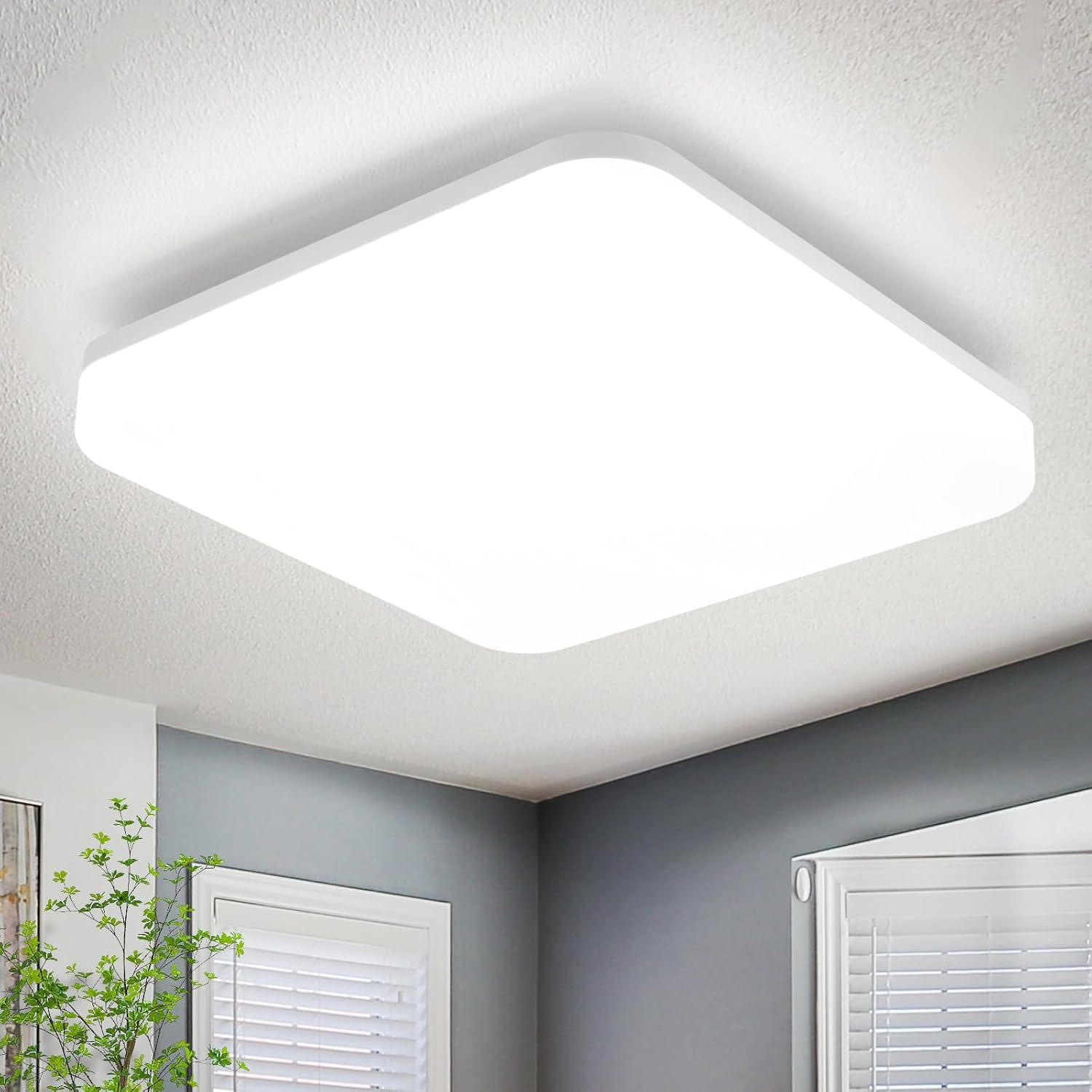 Una lámpara de techo cuadrada blanca e iluminada ilumina una habitación con paredes grises y ventana.