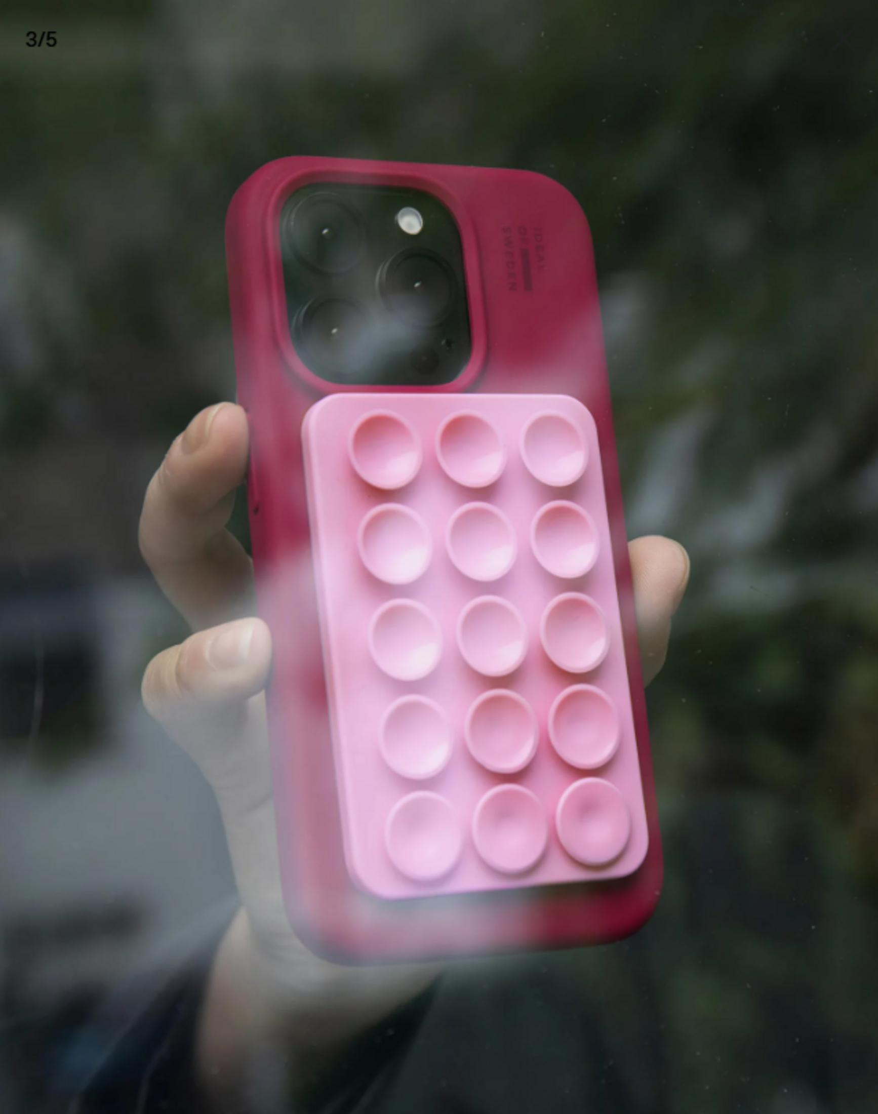 Eine Hand hält ein pinkes Handy mit einem Pop-It-Griff.