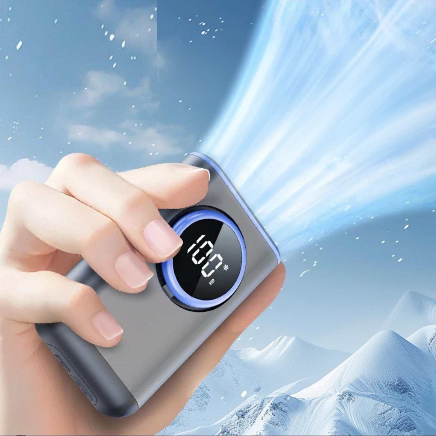 Eine Hand hält ein graues Gerät mit einem 100% Display vor einer verschneiten Berglandschaft.