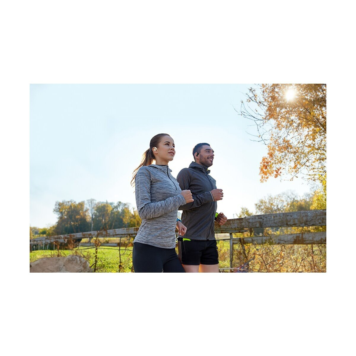 Ein Mann und eine Frau joggen nebeneinander im Freien bei Sonnenschein.