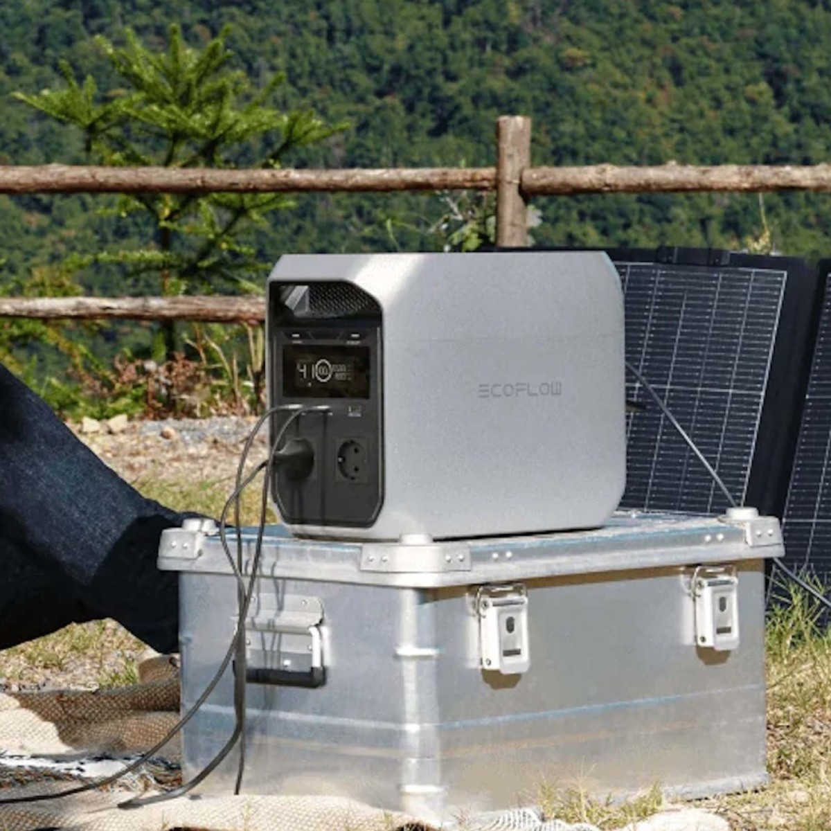 Een zilverkleurig EcoFlow-station staat buiten op een metalen kist, bij zonnepanelen.