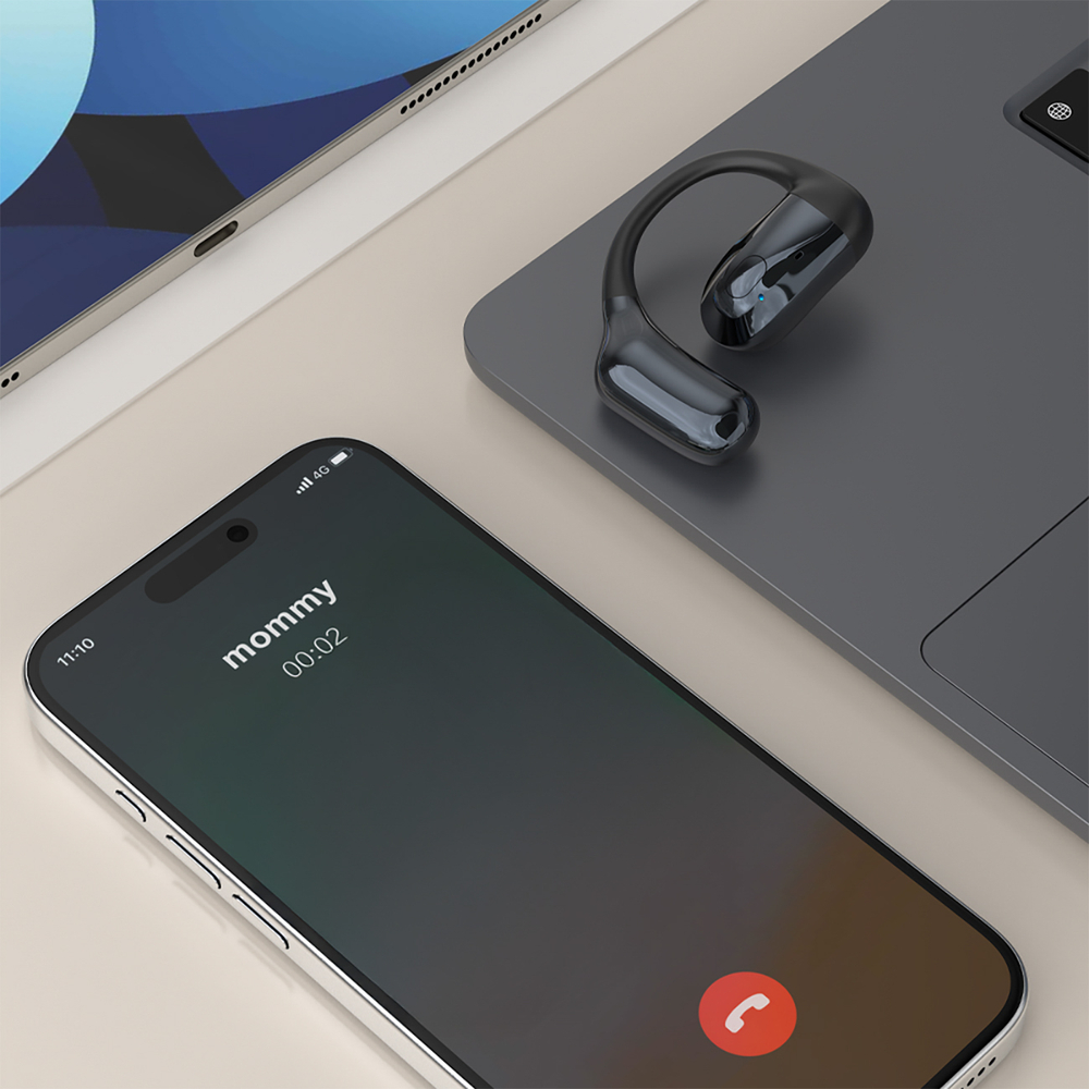 Auricolare wireless nero su un laptop accanto a uno smartphone con schermo di chiamata in arrivo.