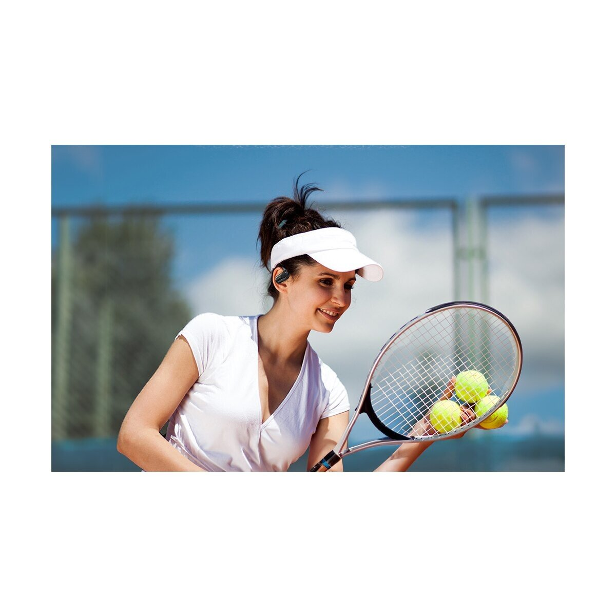 Eine Tennisspielerin mit weißem Visor und Kopfhörern hält einen Schläger mit Bällen.