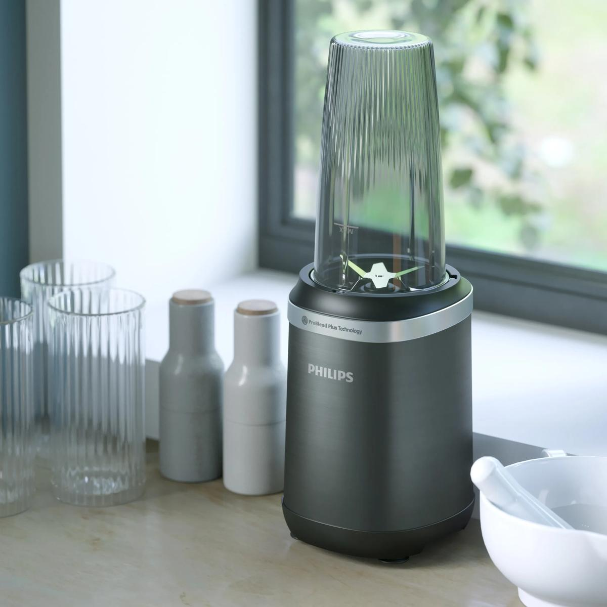 A black Philips blender sits on a kitchen counter next to glasses and a bowl.