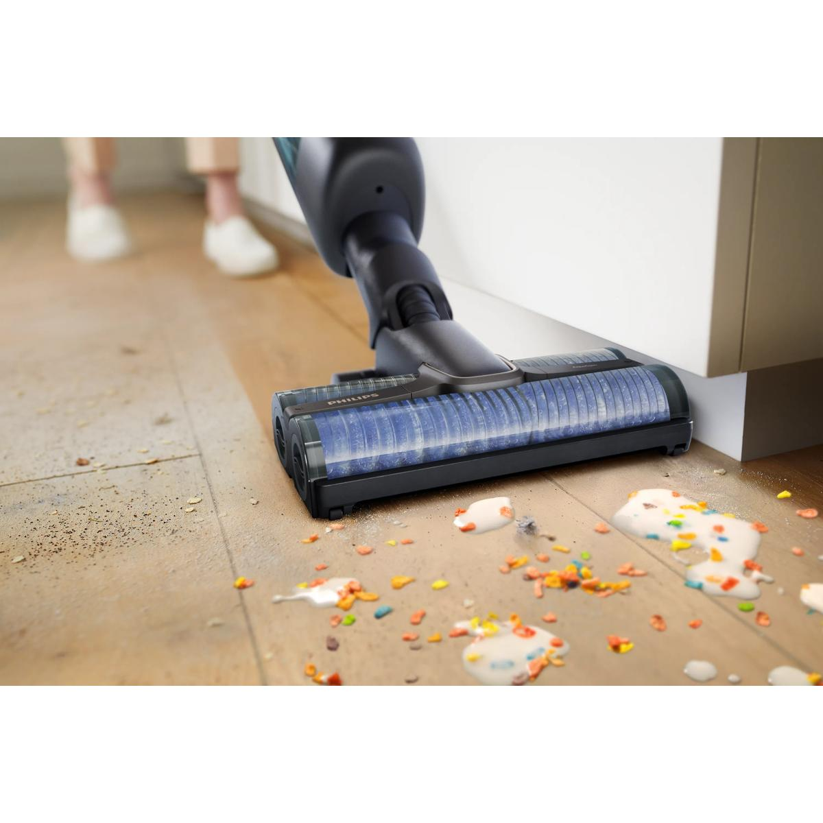 Głowica odkurzacza czyści rozlane jedzenie i kurz na drewnianej podłodze.