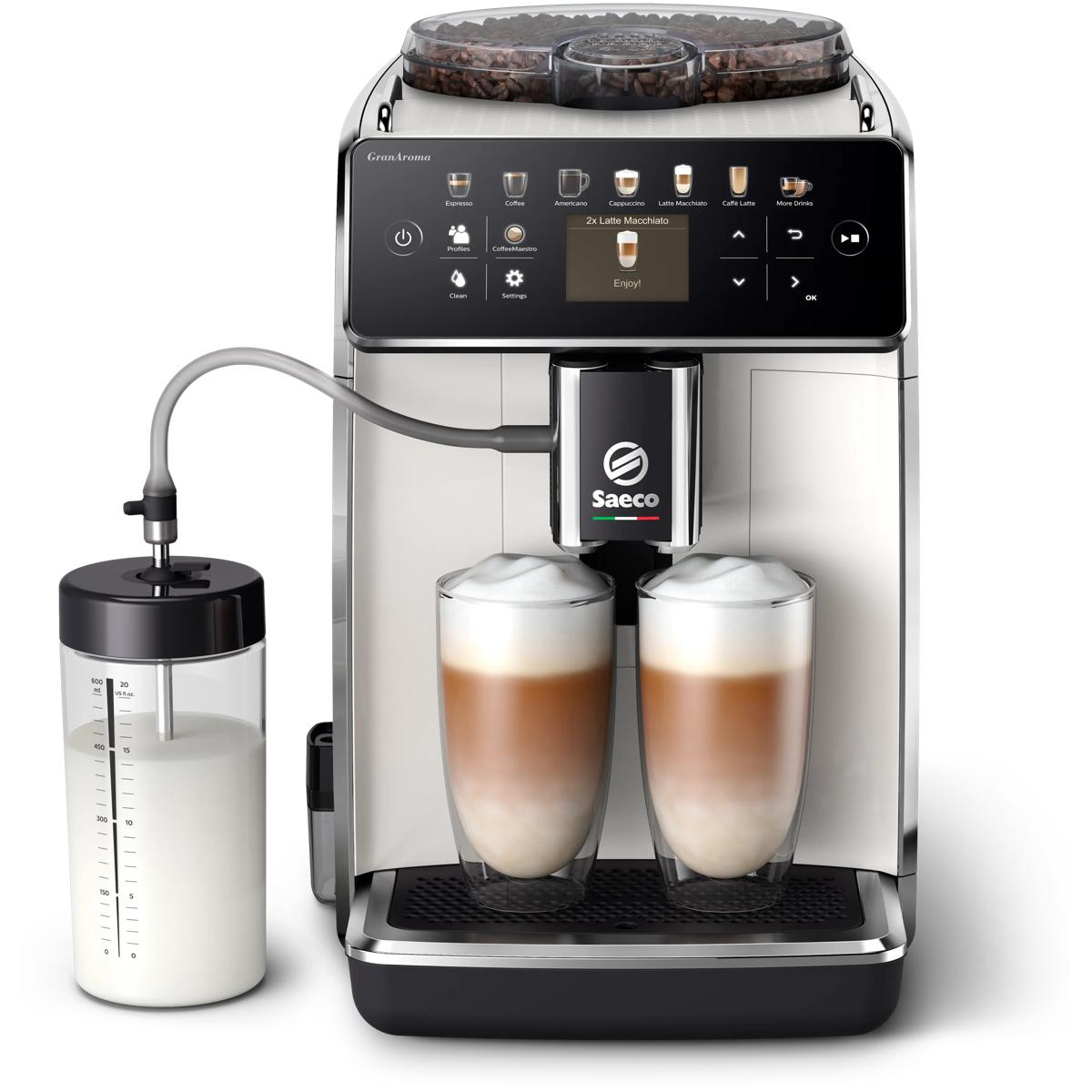 Una cafetera blanca con dos vasos de latte macchiato y una jarra de leche.