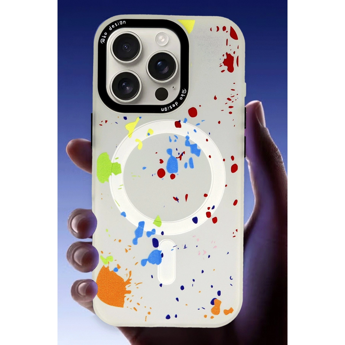 Bir el, üç kamerası ve renkli boya sıçramaları olan beyaz bir telefon kılıfı tutuyor.