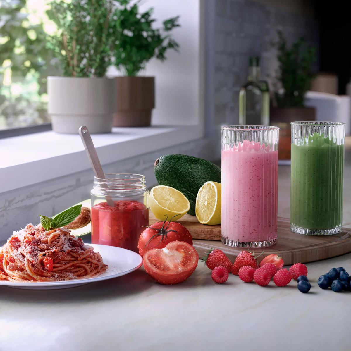 Spaghetti z sosem pomidorowym, owocami i smoothie na blacie kuchennym.