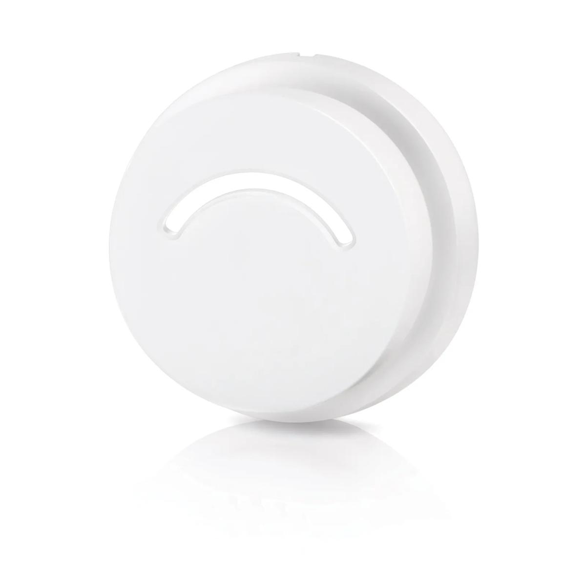 A white, round object with a curved cutout, reflecting on a white surface.