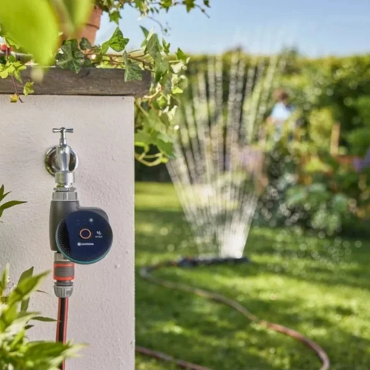 Ein digitaler Wasserhahn-Controller mit Schlauch und Sprinkler im Garten.