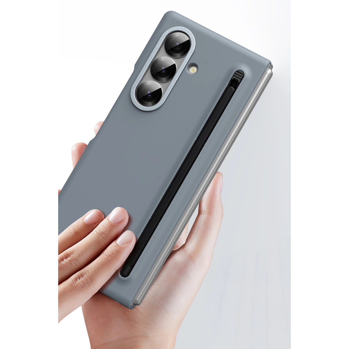 Üç kameralı gri telefon, styluslu, ellerde tutuluyor.